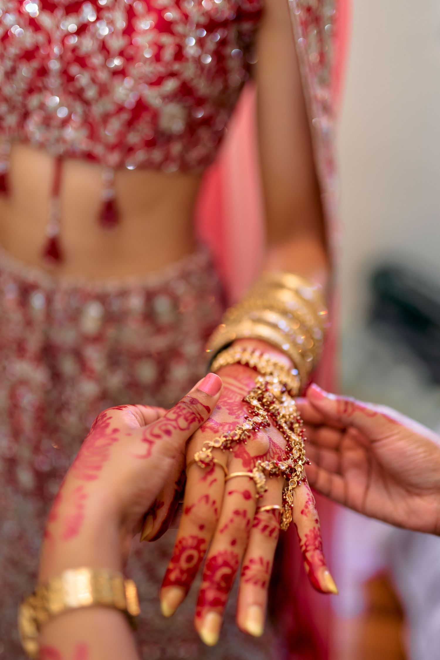 Detailed shots of intricate henna designs and gold jewelry on bride's hands.