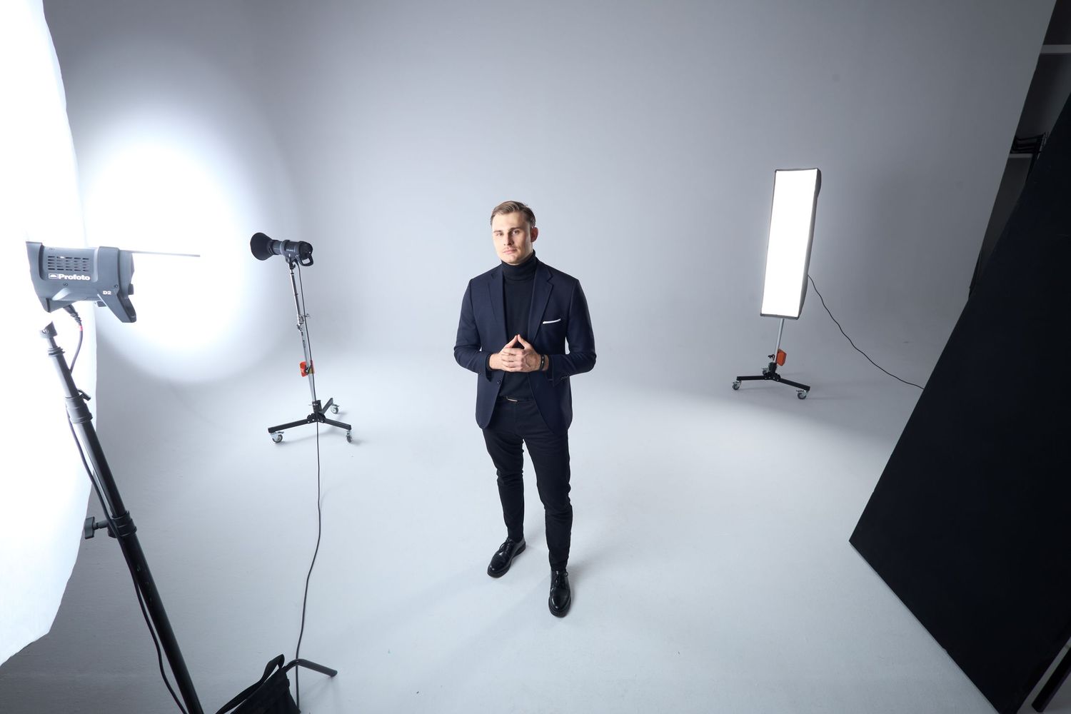 Białe studio fotograficzne z oświetleniem i osobą w ciemnym garniturze. Fotografia biznesowa Lublin.