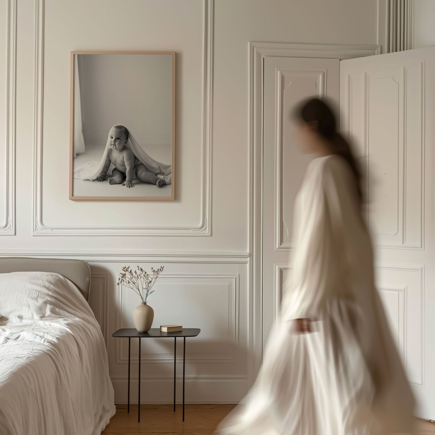 A minimalist white bedroom features a framed dog portrait and an ethereal figure in flowing white dress moving past.