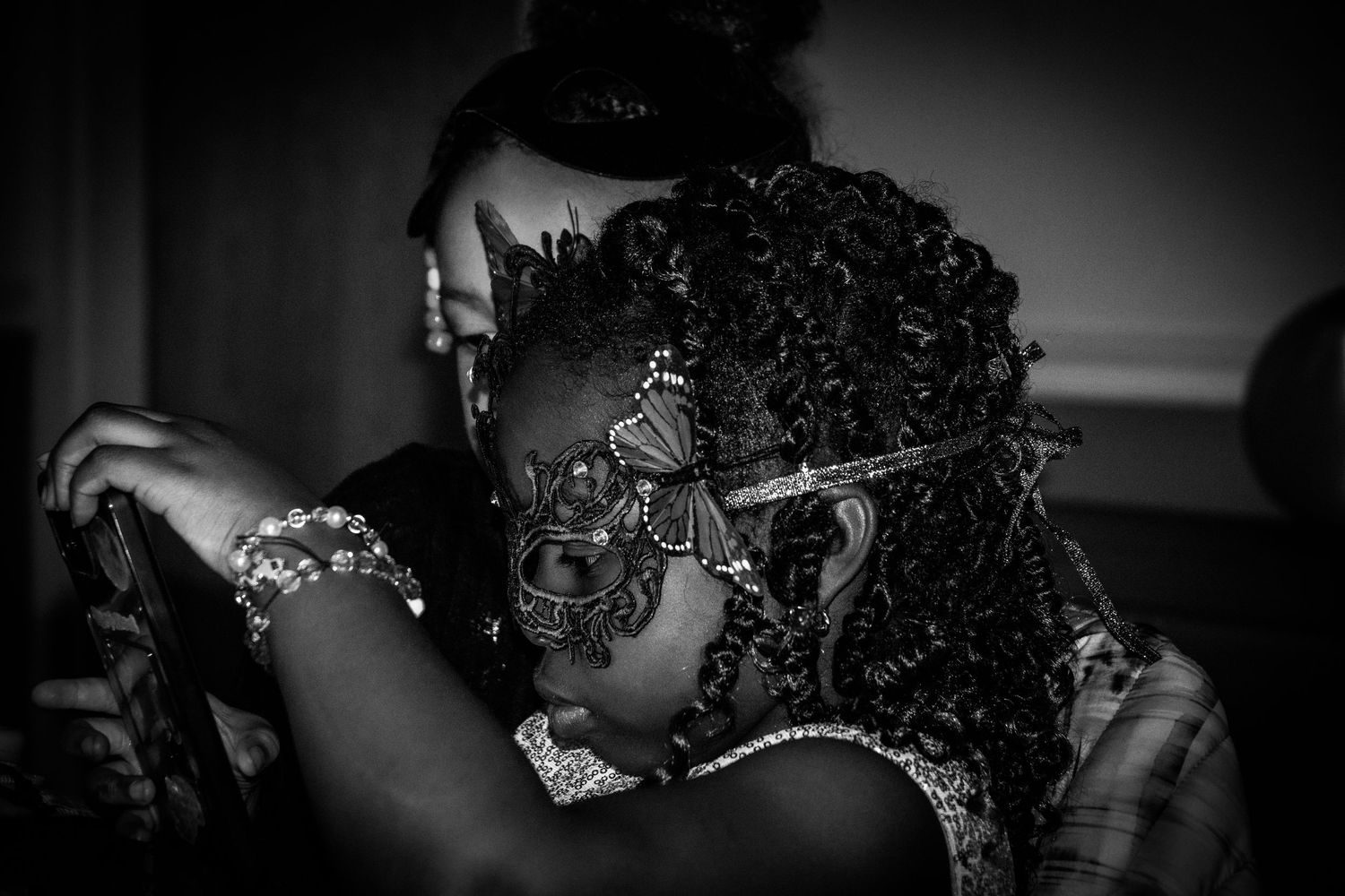 Partygoers in formal attire and masks dance together at an elegant masquerade ball.