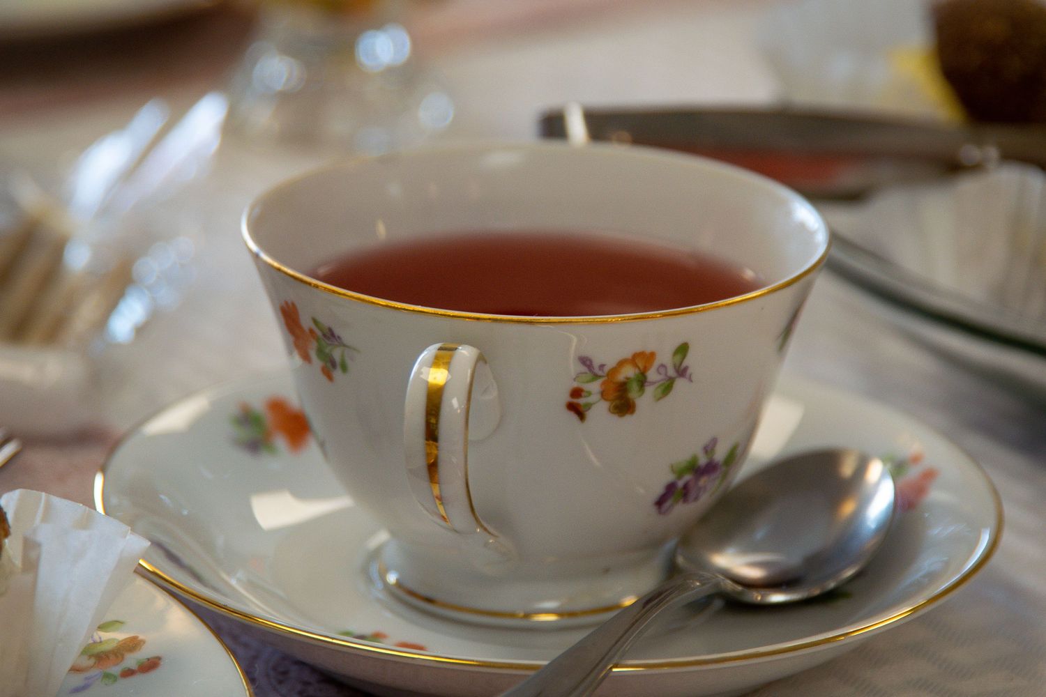 A delicate teacup with small floral designs and gold trim on a saucer.