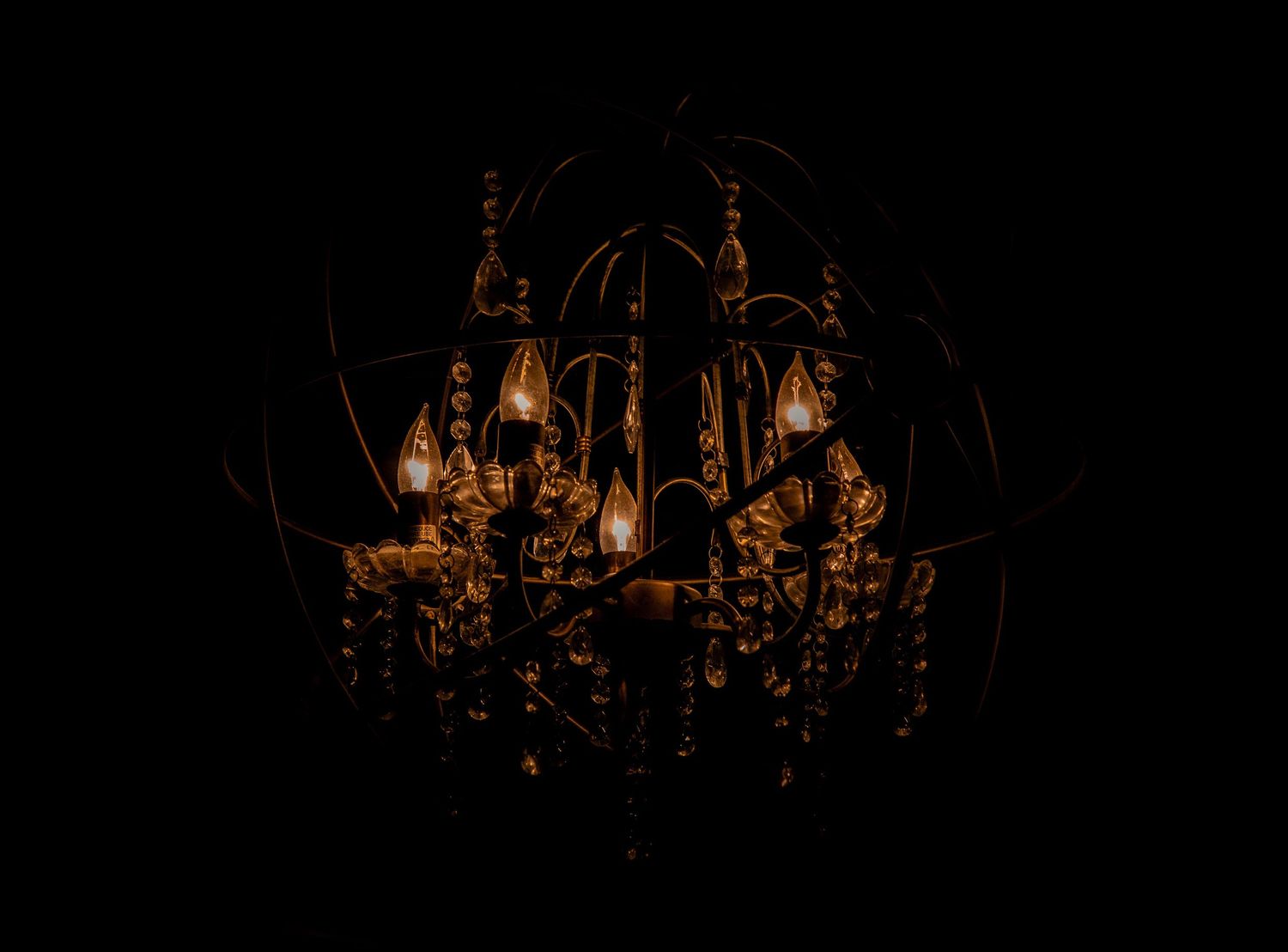 Ornate crystal chandelier glows dramatically in darkness at formal event.