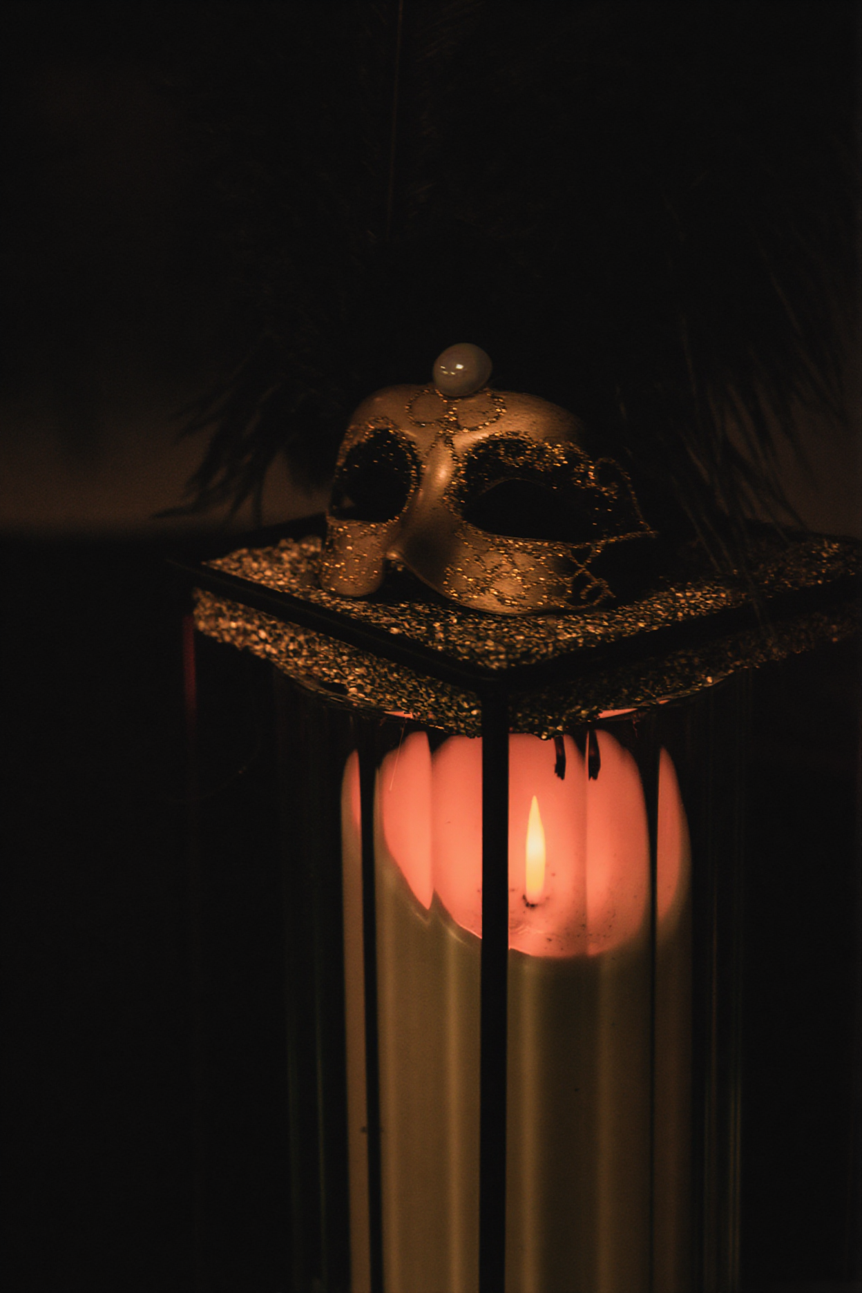 Decorative lantern with glowing orange light creates atmospheric shadows in darkness.