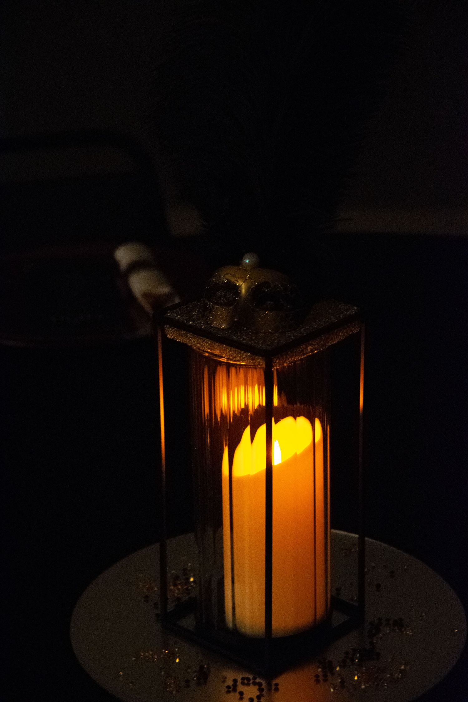 Glowing lantern centerpiece casts warm light through glass panels in dark room.