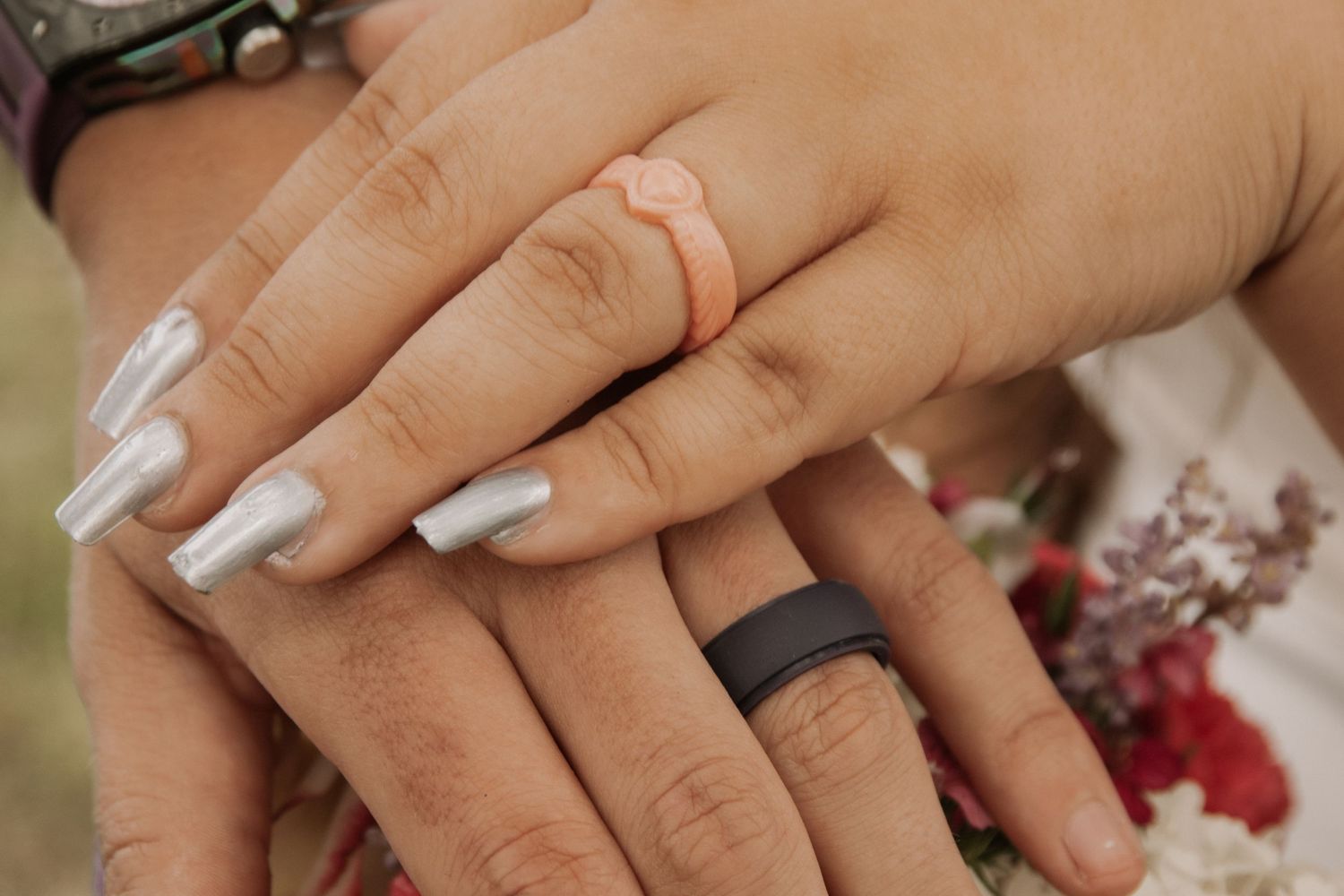 Elegant engagement ring sparkles on hand with manicured nails against soft background.