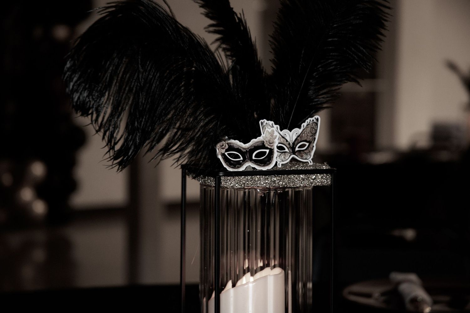 Elegant black masquerade masks with feathers and decorative details displayed against a dark background.