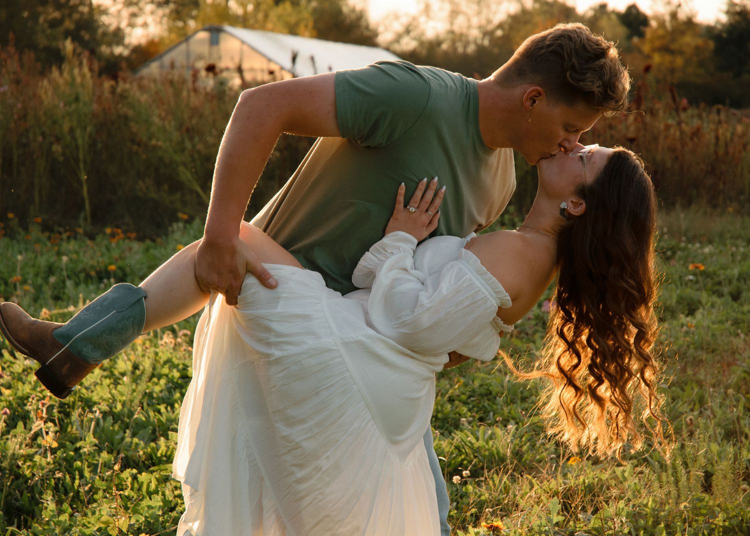 Romantic dance pose in golden sunlit meadow during engagement session.