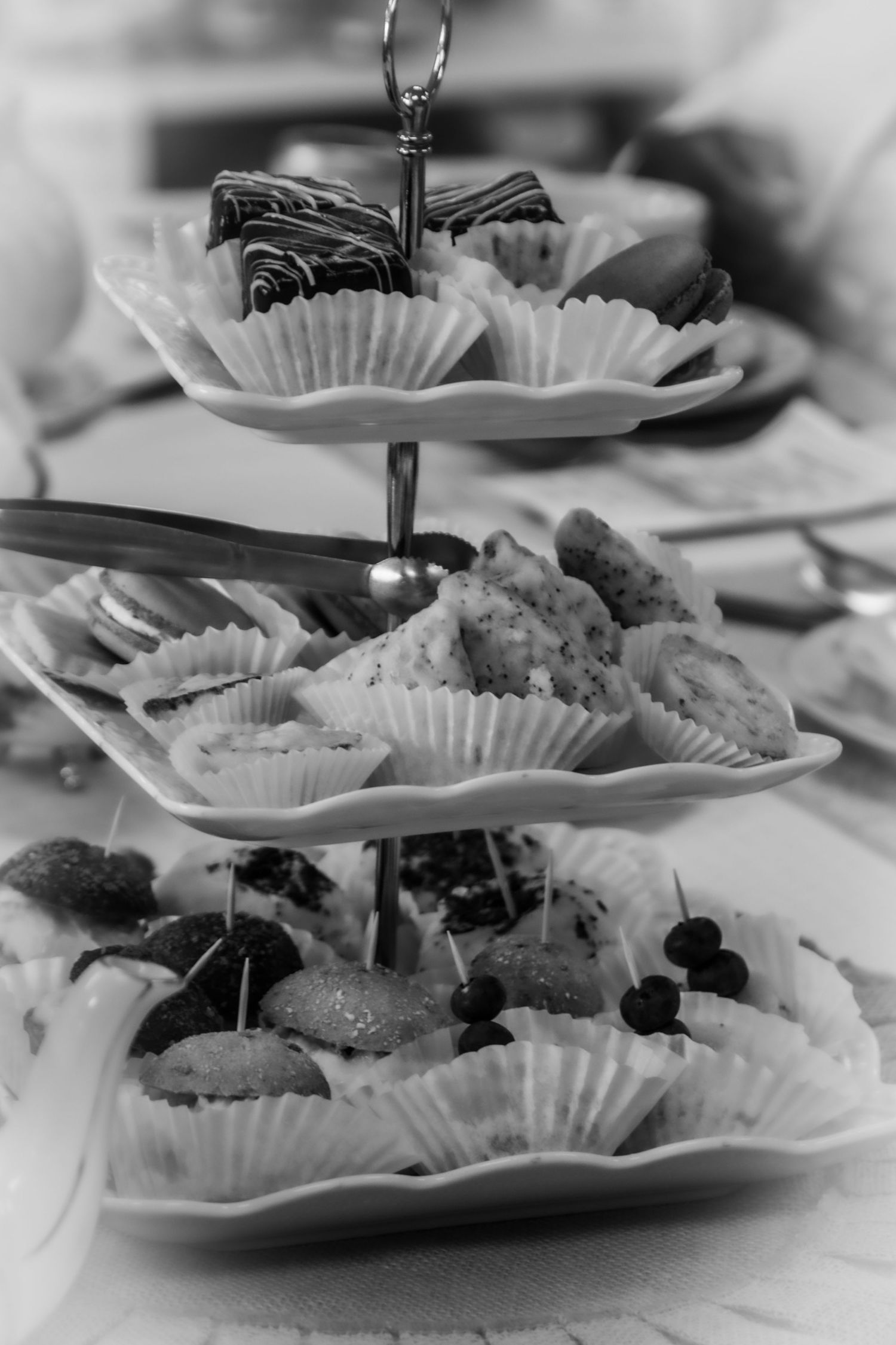 A three-tiered serving stand filled with assorted pastries and treats in paper liners.