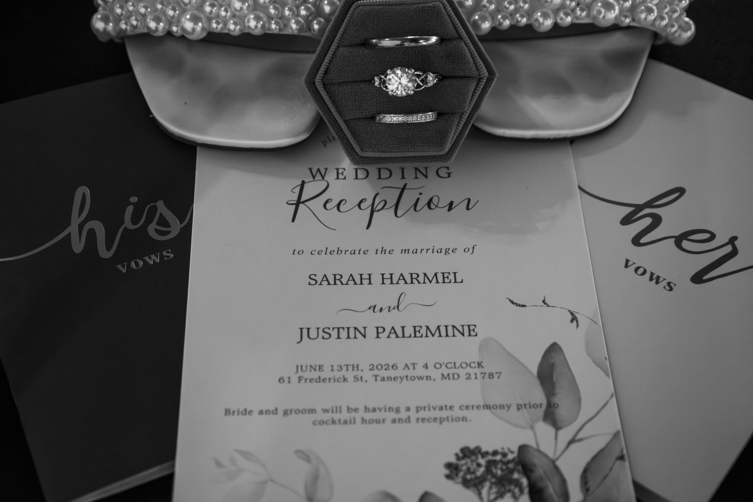 Black and white wedding reception invitation for Sarah Harmel and Justin Palemine displayed with rings and vow books.