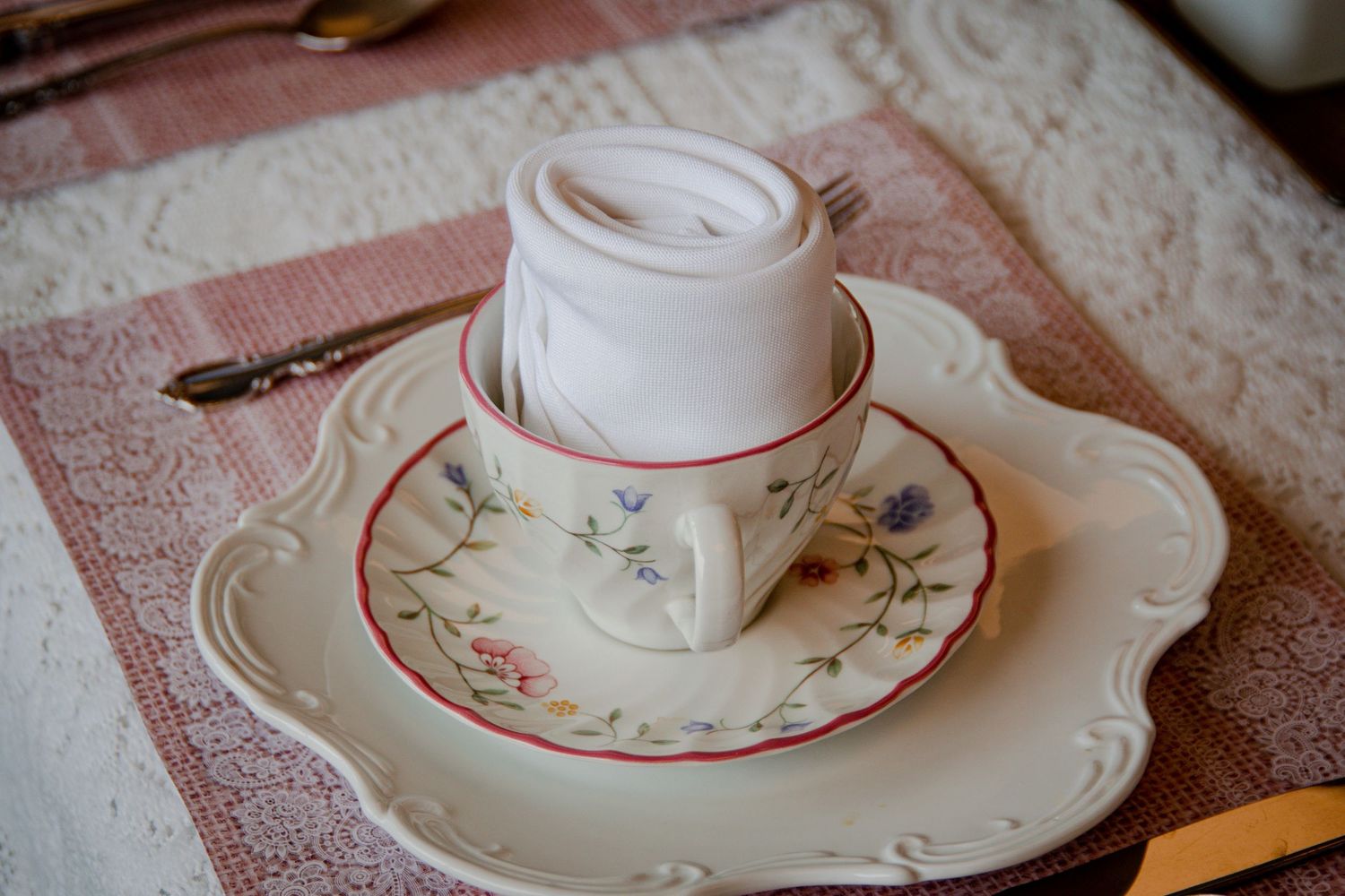 A delicate teacup and saucer with floral pattern displayed on an ornate plate.