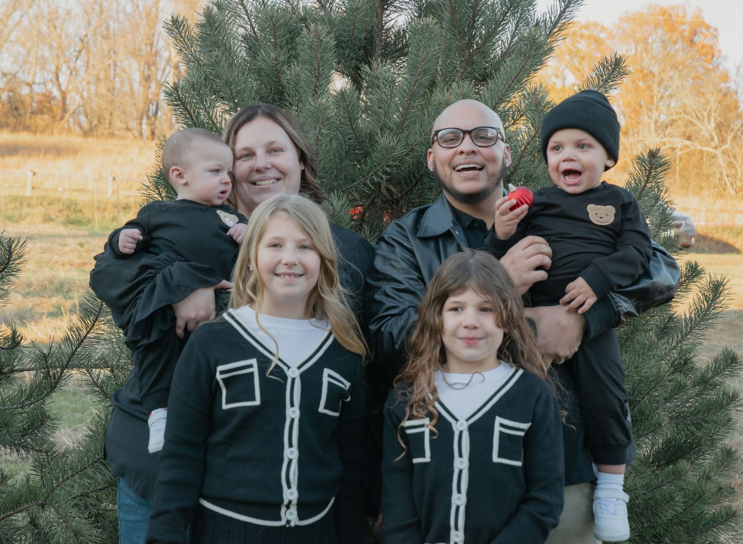 Family group photo session at a Christmas tree farm during golden hour.