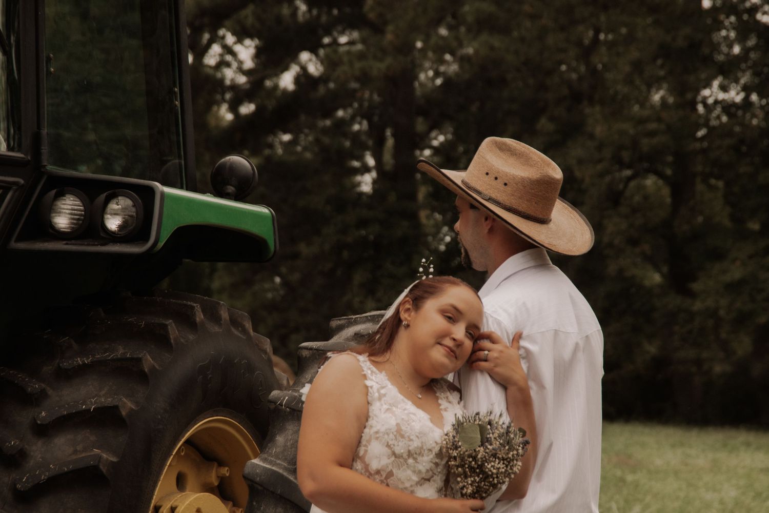 Romantic country wedding scene with tractors and natural outdoor setting.