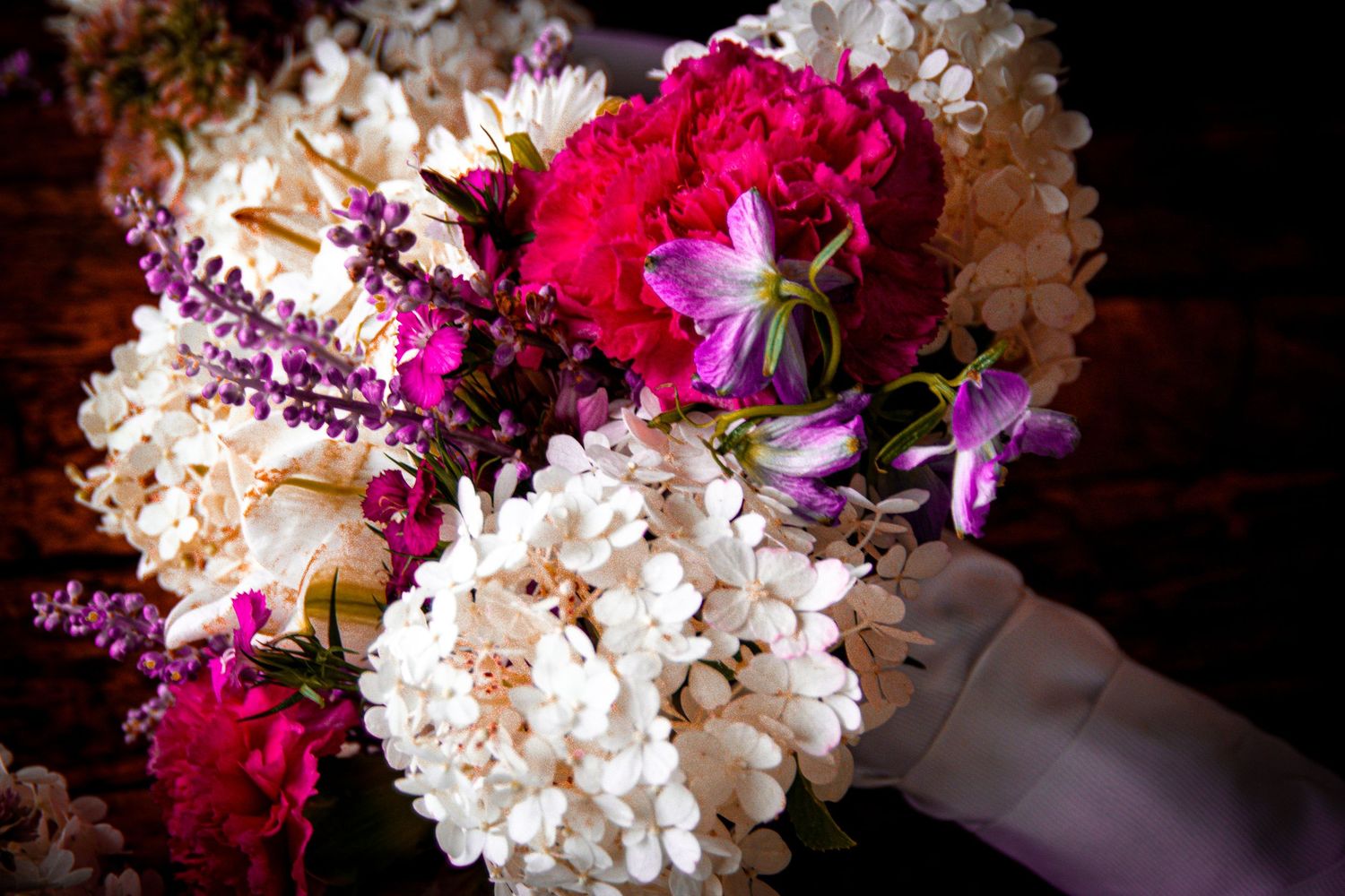 Vibrant pink and white floral wedding arrangements against dark background.