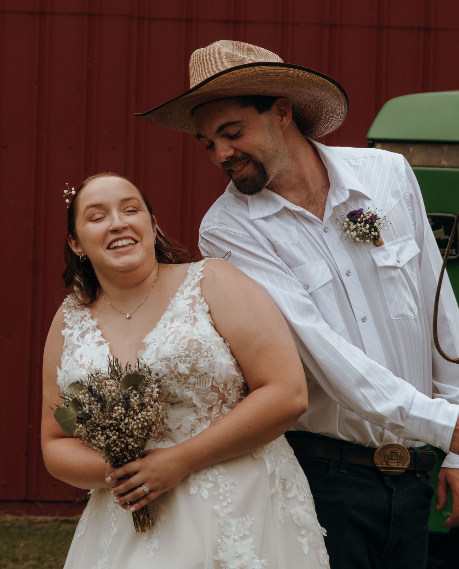 Rustic country wedding scene with cowboy hats and white lace dress against red barn.