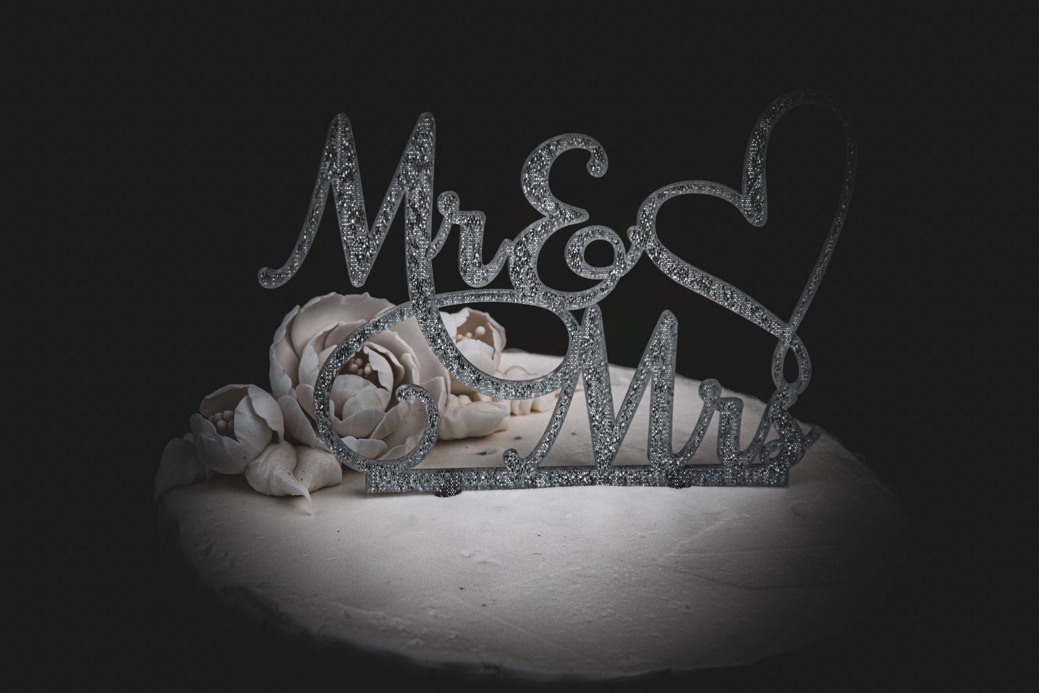 Glittery Mr and Mrs wedding sign decoration on dark background.
