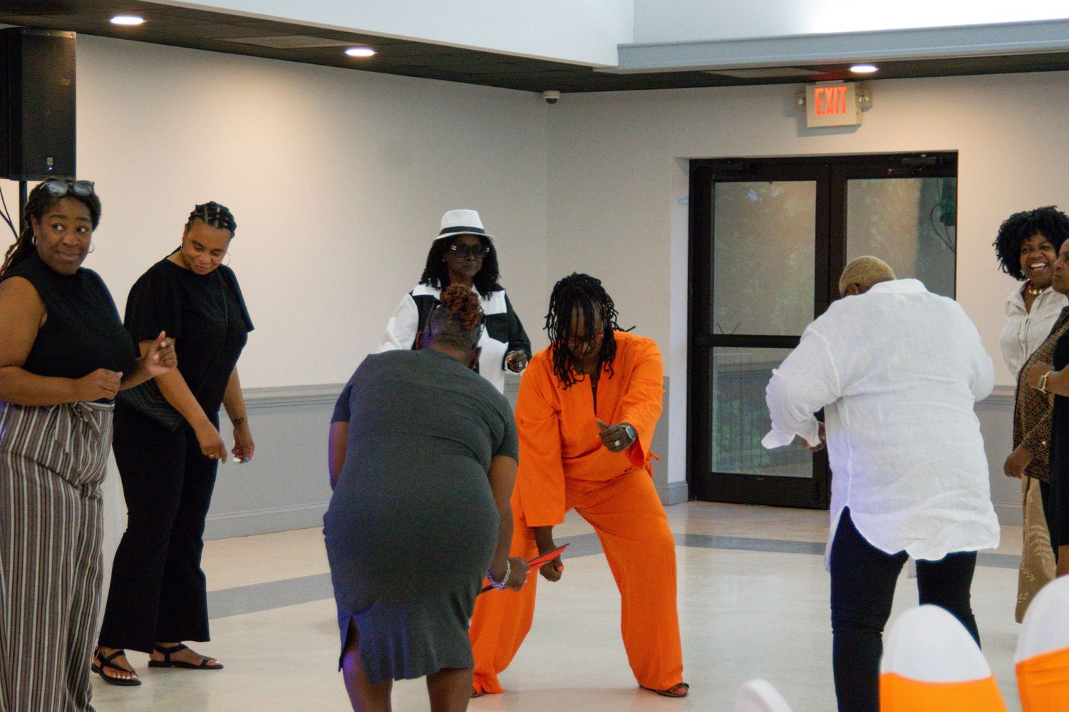 Guests dancing and socializing at an indoor celebration with orange and white decor.