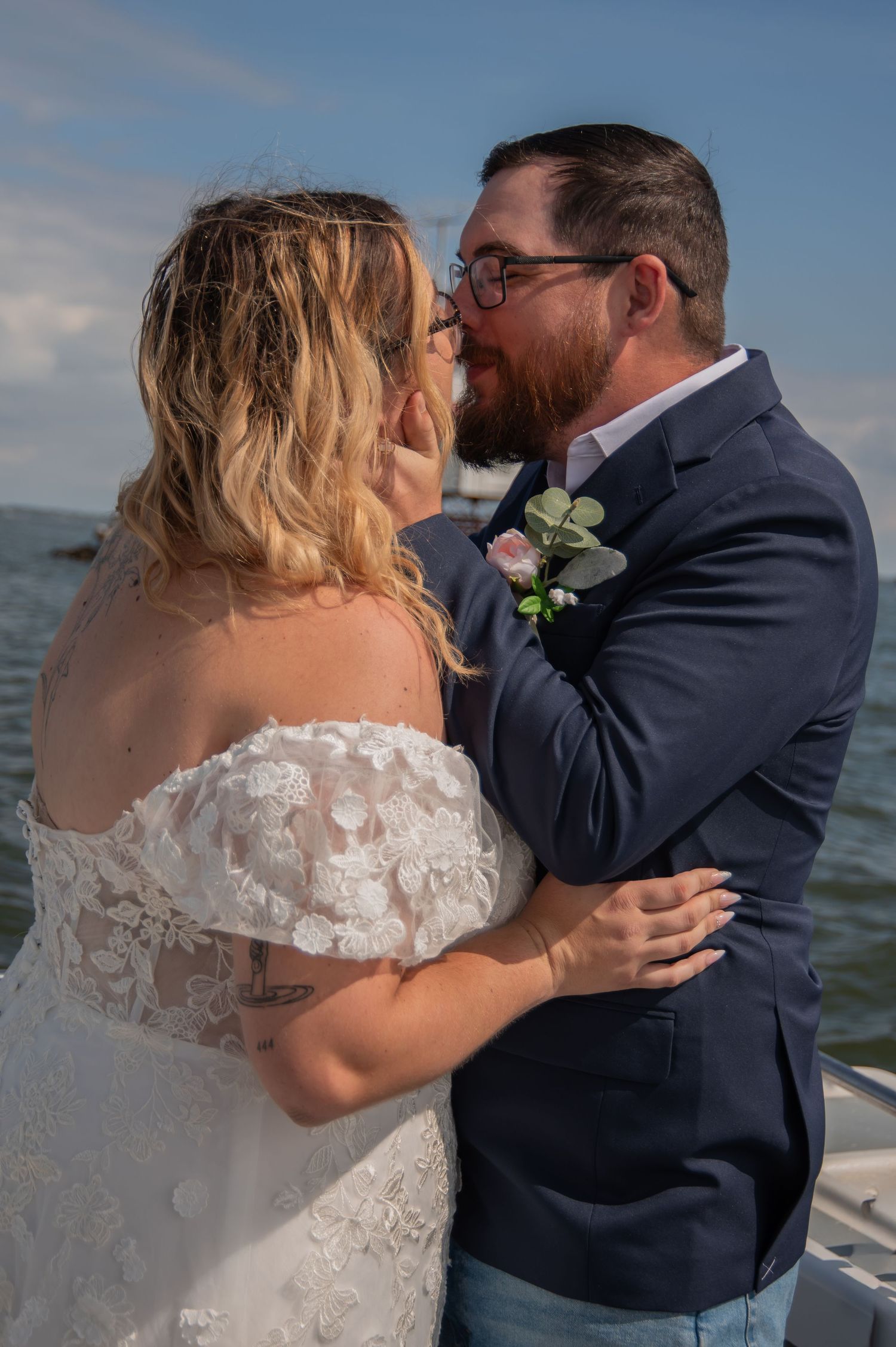 Bride and groom share a romantic moment on a boat, with the ocean in the background on their wedding day.