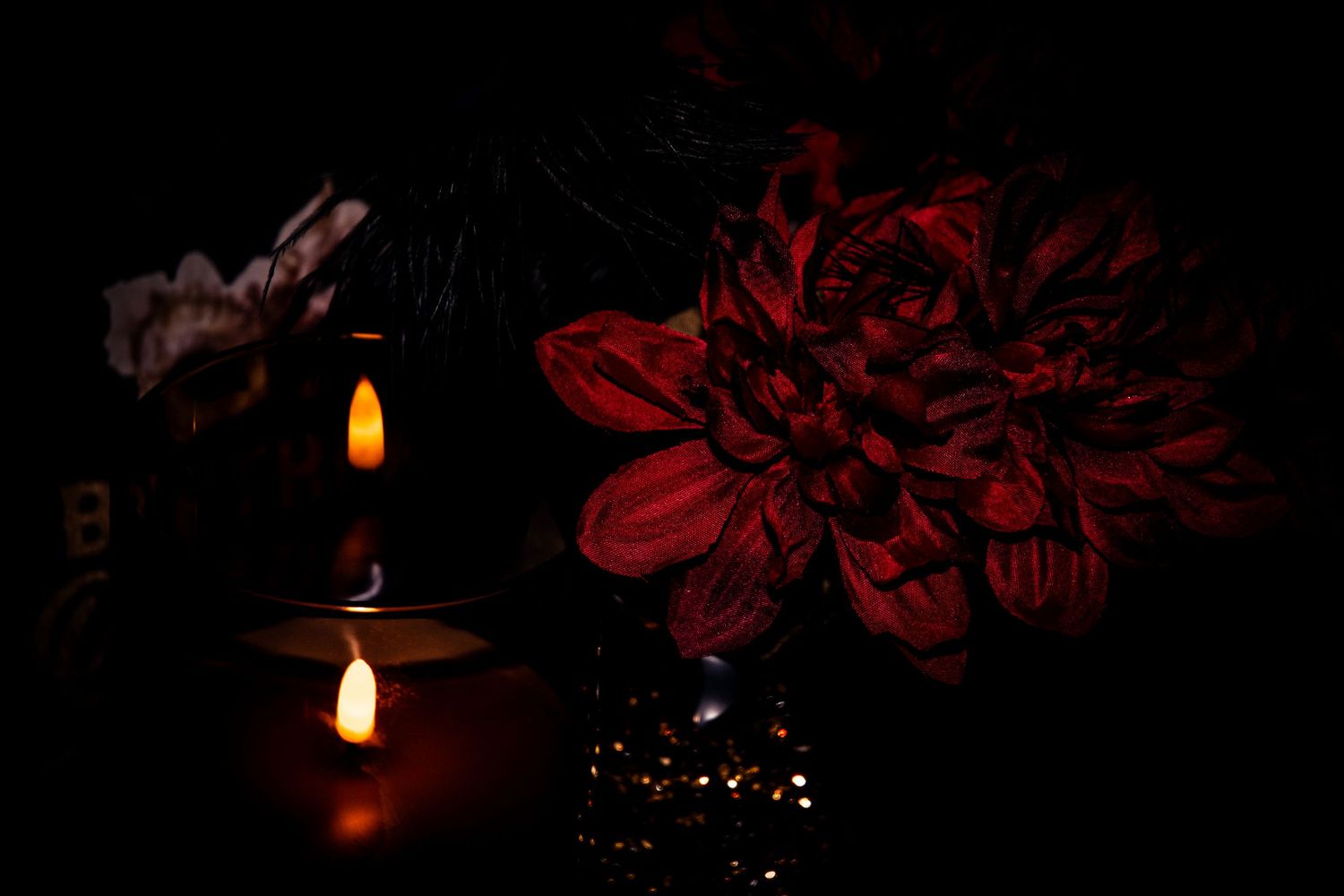 Deep red flowers and glowing candles create a romantic ambiance in low lighting.