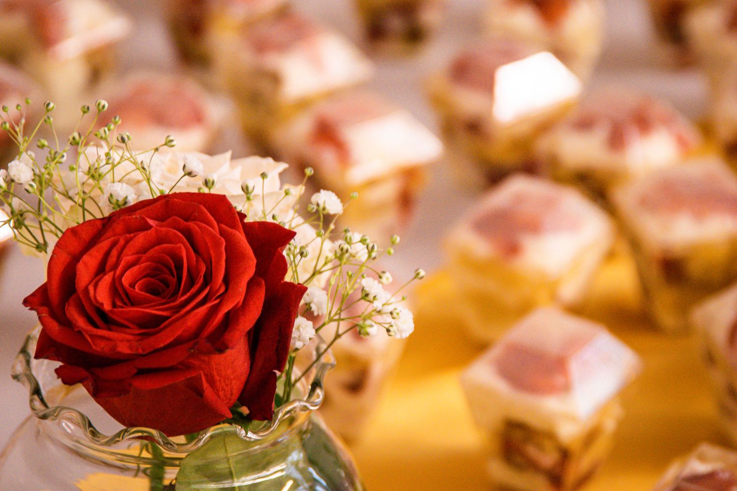 Close-up of red roses and delicate floral arrangements on golden surface.