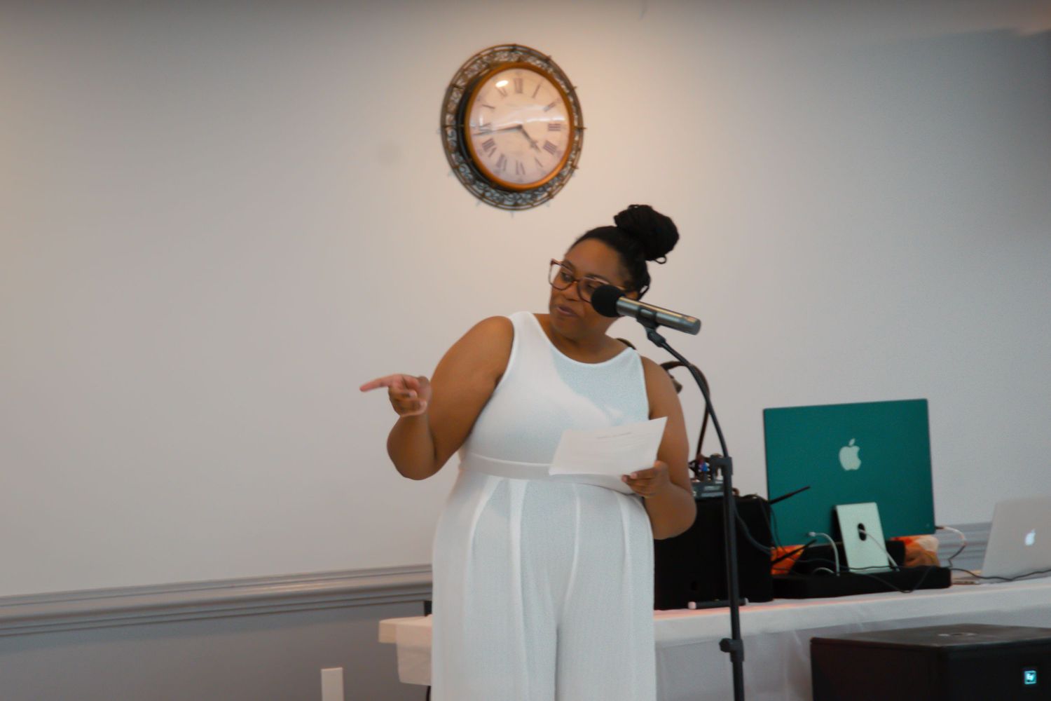 A speaker presenting at a celebration event with a laptop and microphone.