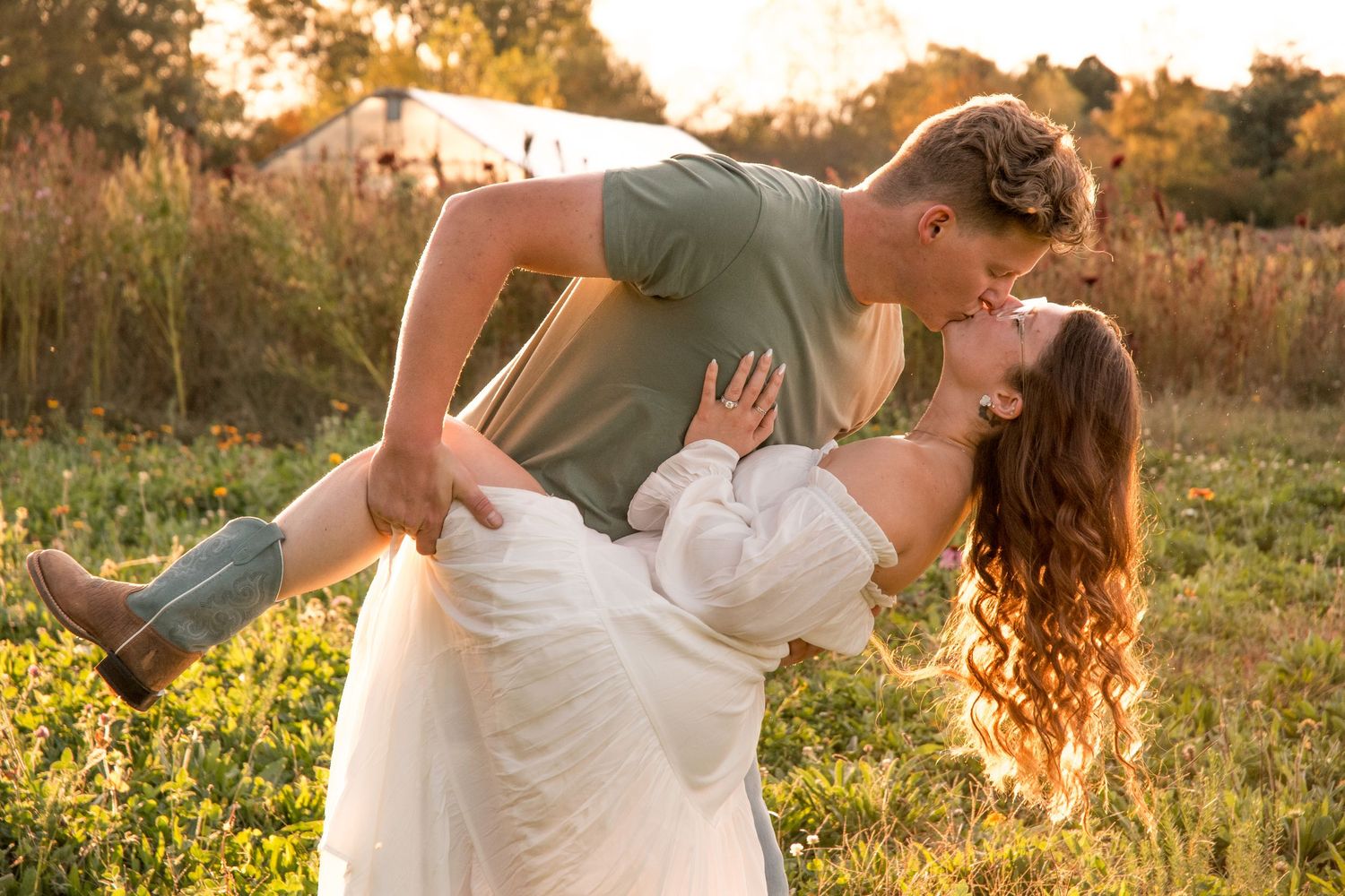 Couple dancing in a golden field during sunset creating romantic silhouettes.