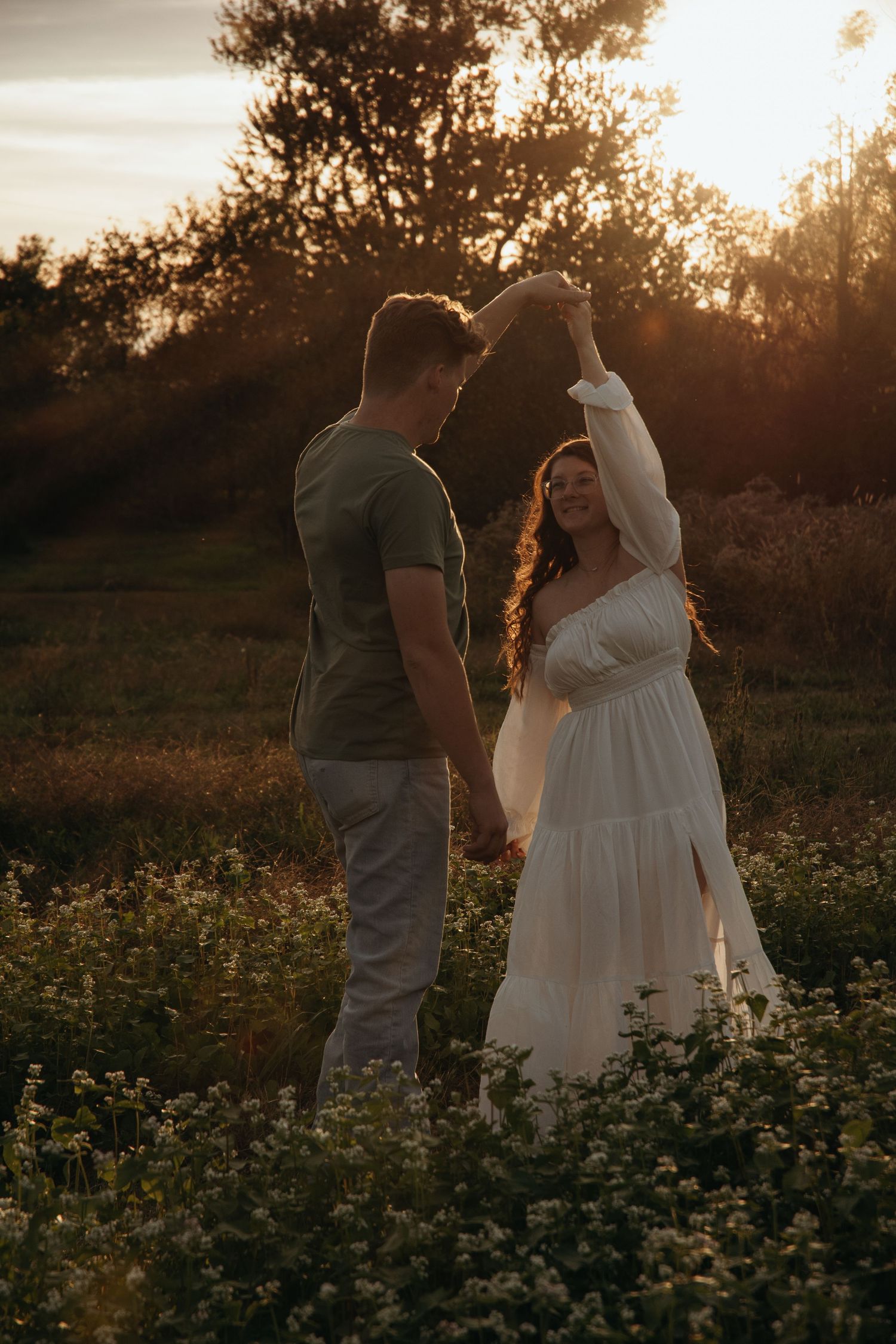 Couple sharing intimate moment in wildflower field during golden hour sunset.