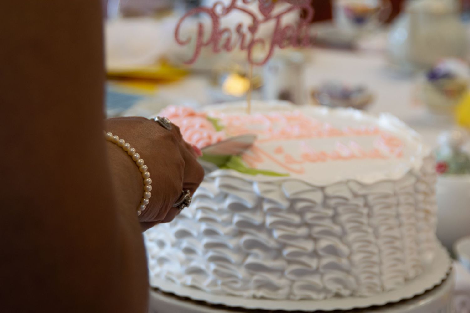 A close-up of a white frosted cake with lace-like piping details.