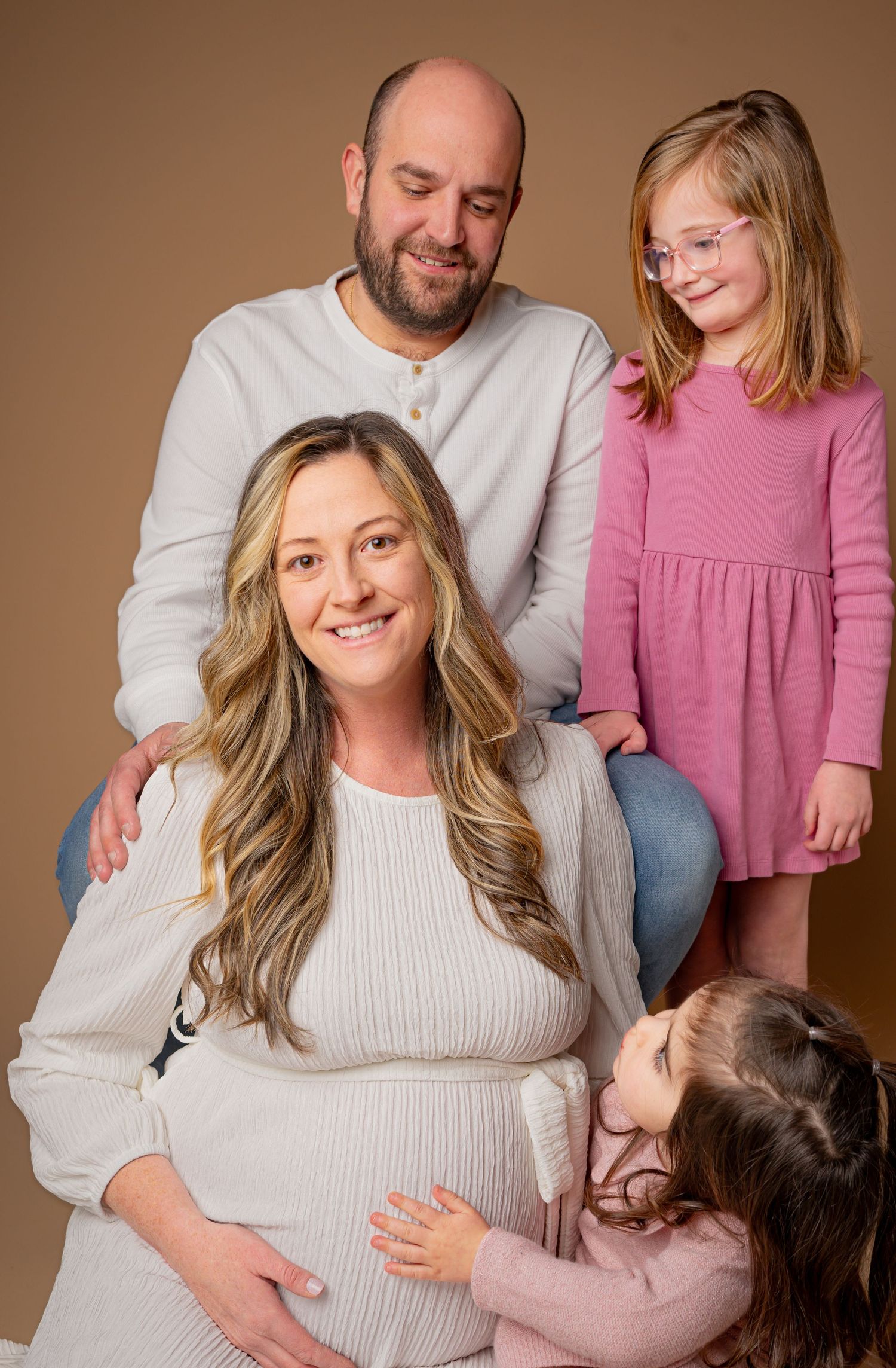 Family looking at mom, the star of her maternity portrait located in a home studio in Palmyra Pa