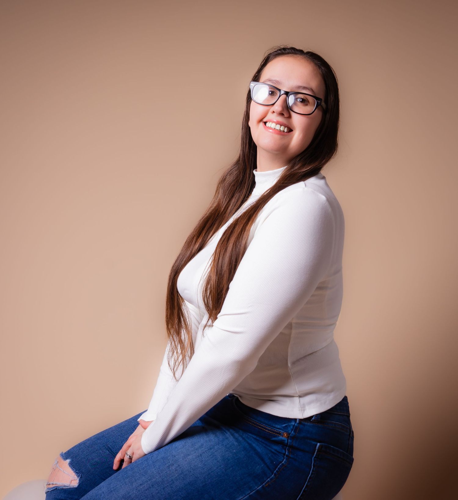 photographer megan delosangeles posing in front of tan backdrop in her home studio near hershey pa