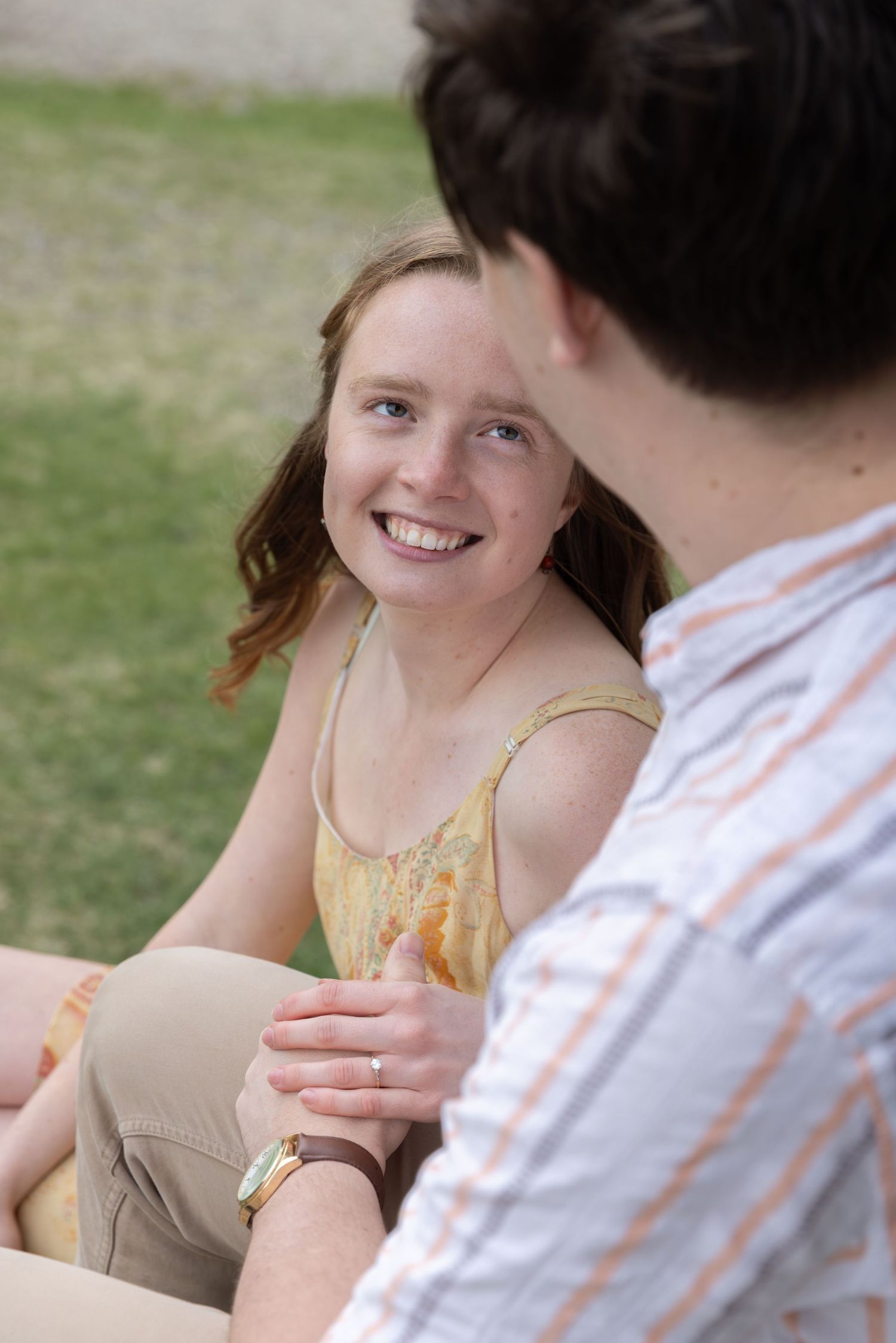 A couple sits outdoors having an intimate conversation while enjoying drinks on a sunny afternoon.