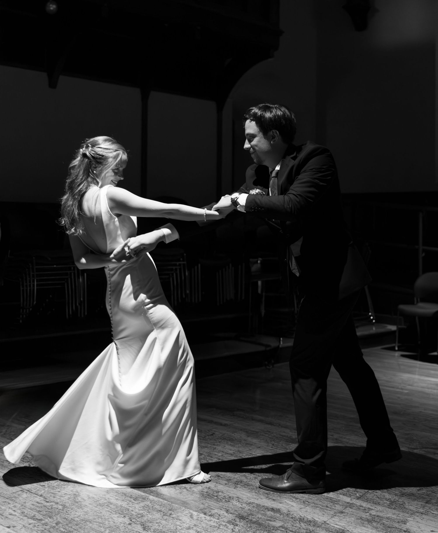 A couple performs an elegant dance in black and white, with the woman in a flowing white gown and man in dark formal attire.