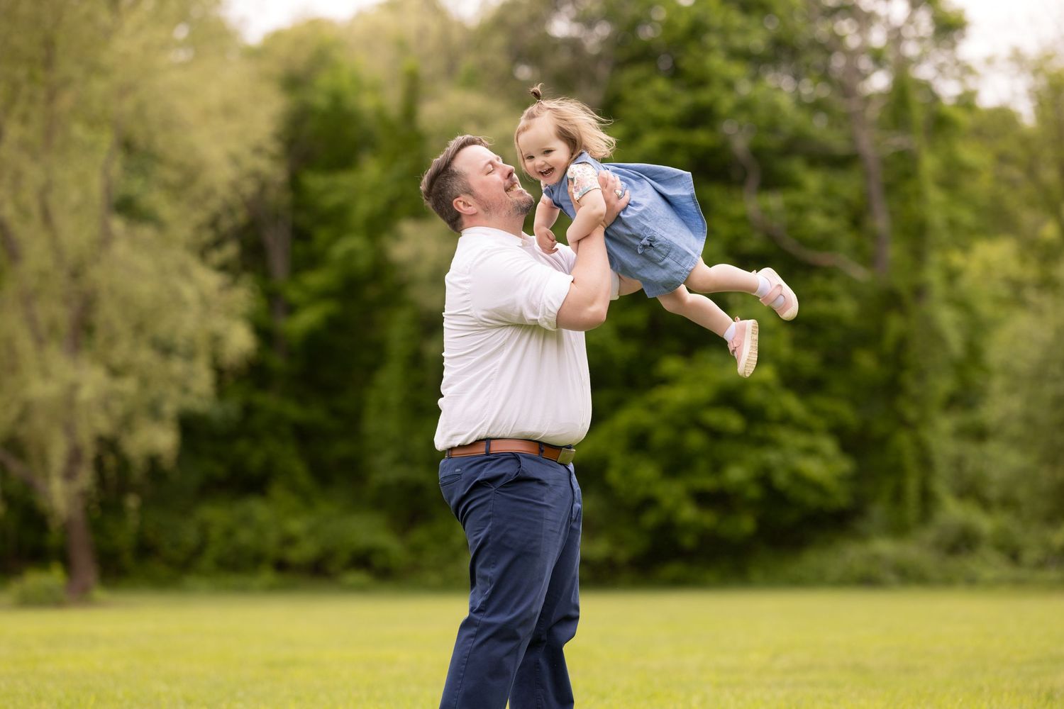 A couple dances together on a grassy lawn during a warm summer day, creating a romantic outdoor moment.