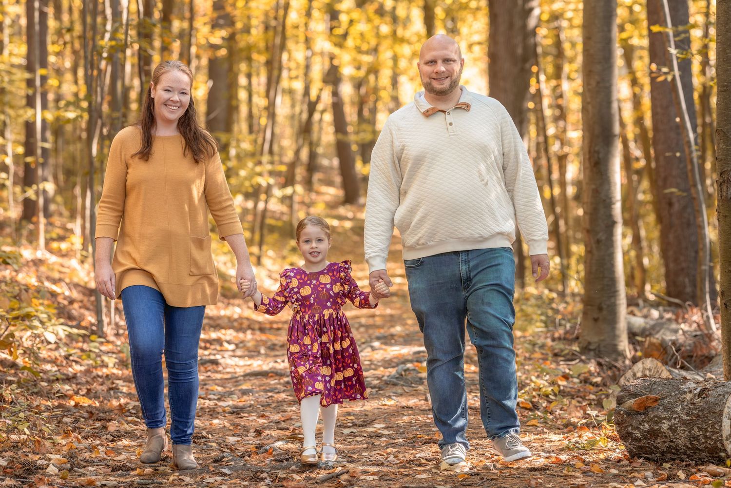 People walking together through a golden autumn forest with fallen leaves during sunset.