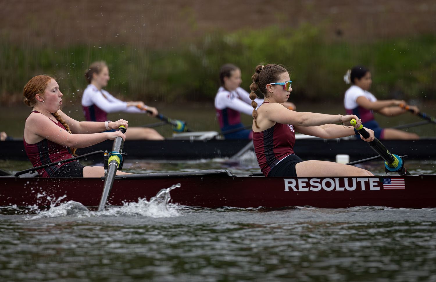Rowing crew team gliding across dark water during competitive race with synchronized movements and oars splashing.