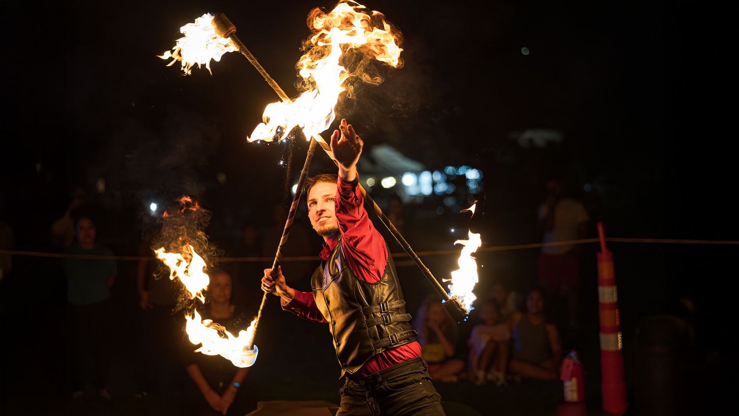A performer spins flaming torches during a nighttime fire dance performance creating dramatic light trails in the darkness.