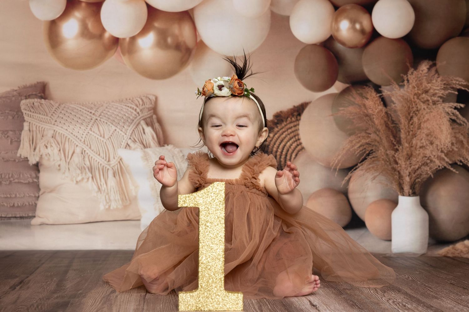 A festive first birthday celebration setup with gold number one decoration, balloons, and soft pink tulle decorations.