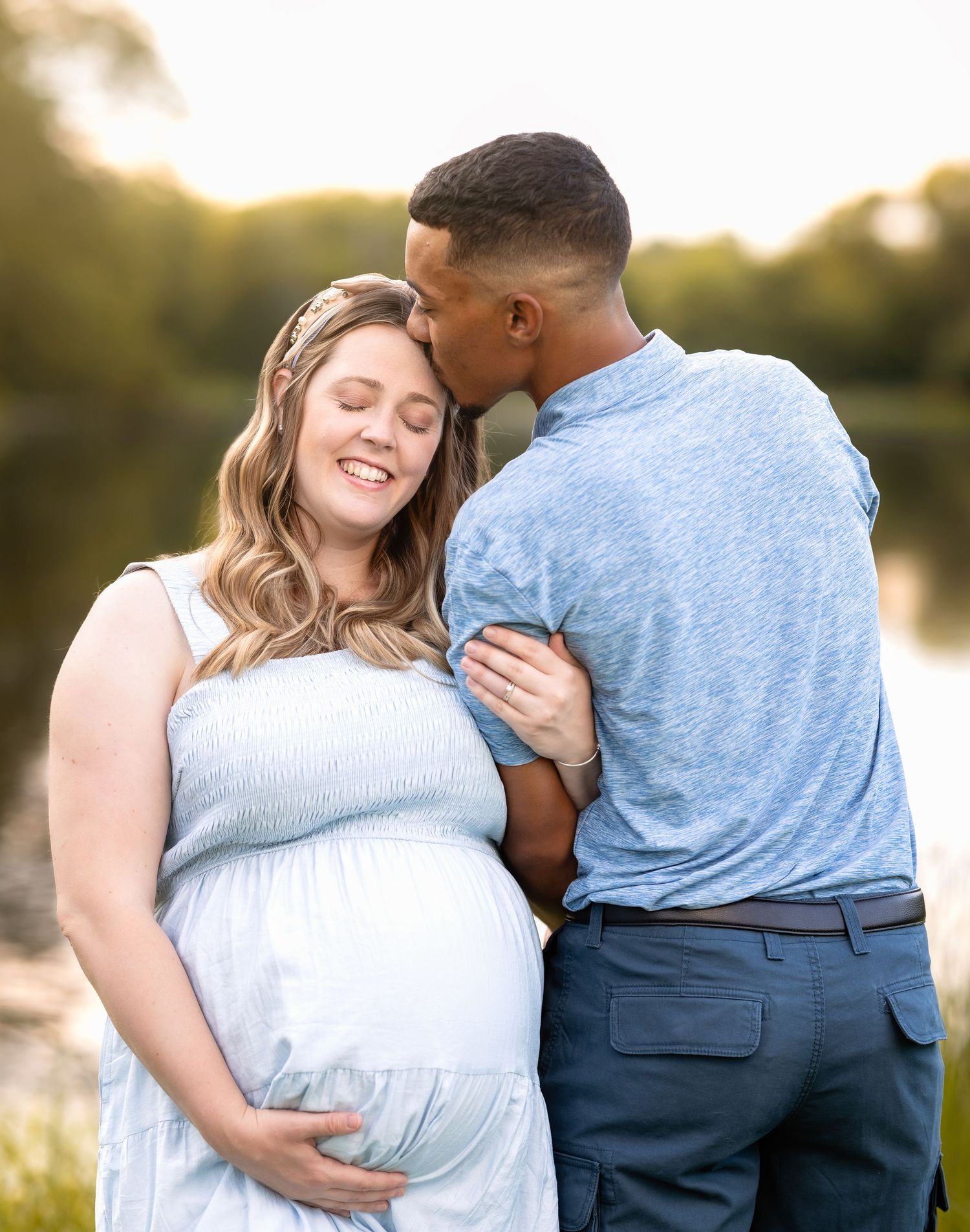 A couple shares an intimate embrace during a golden hour photoshoot by a lake in a romantic outdoor setting.