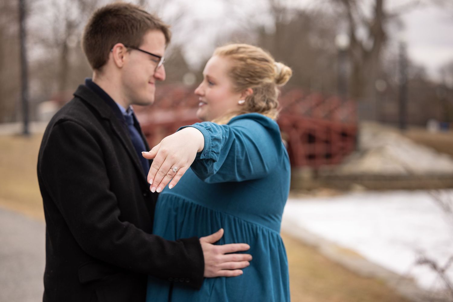 A couple in formal winter attire shares an intimate moment during a snowy outdoor photo session.