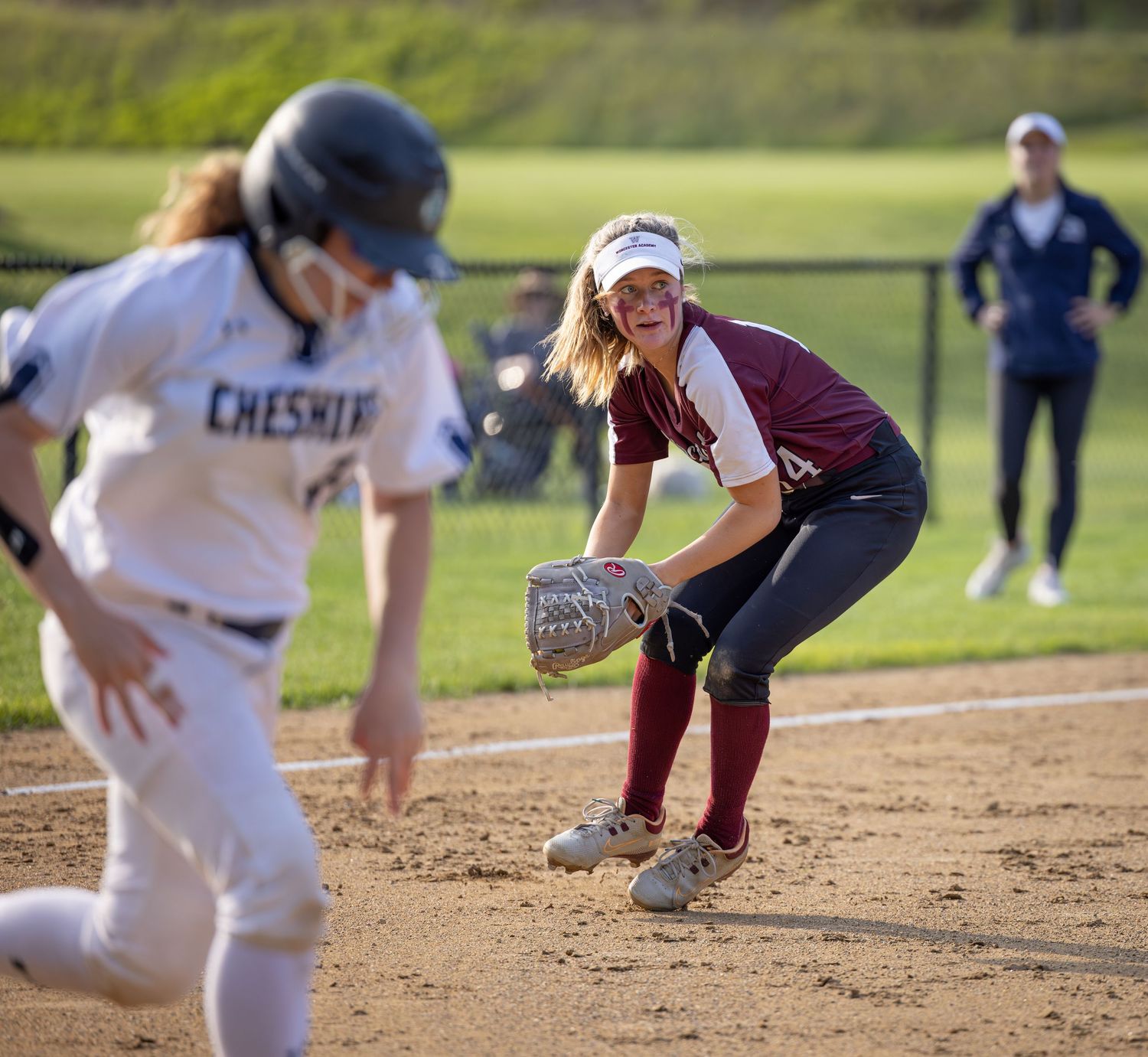 A softball player slides into base during a competitive game while the defender attempts to make the tag.