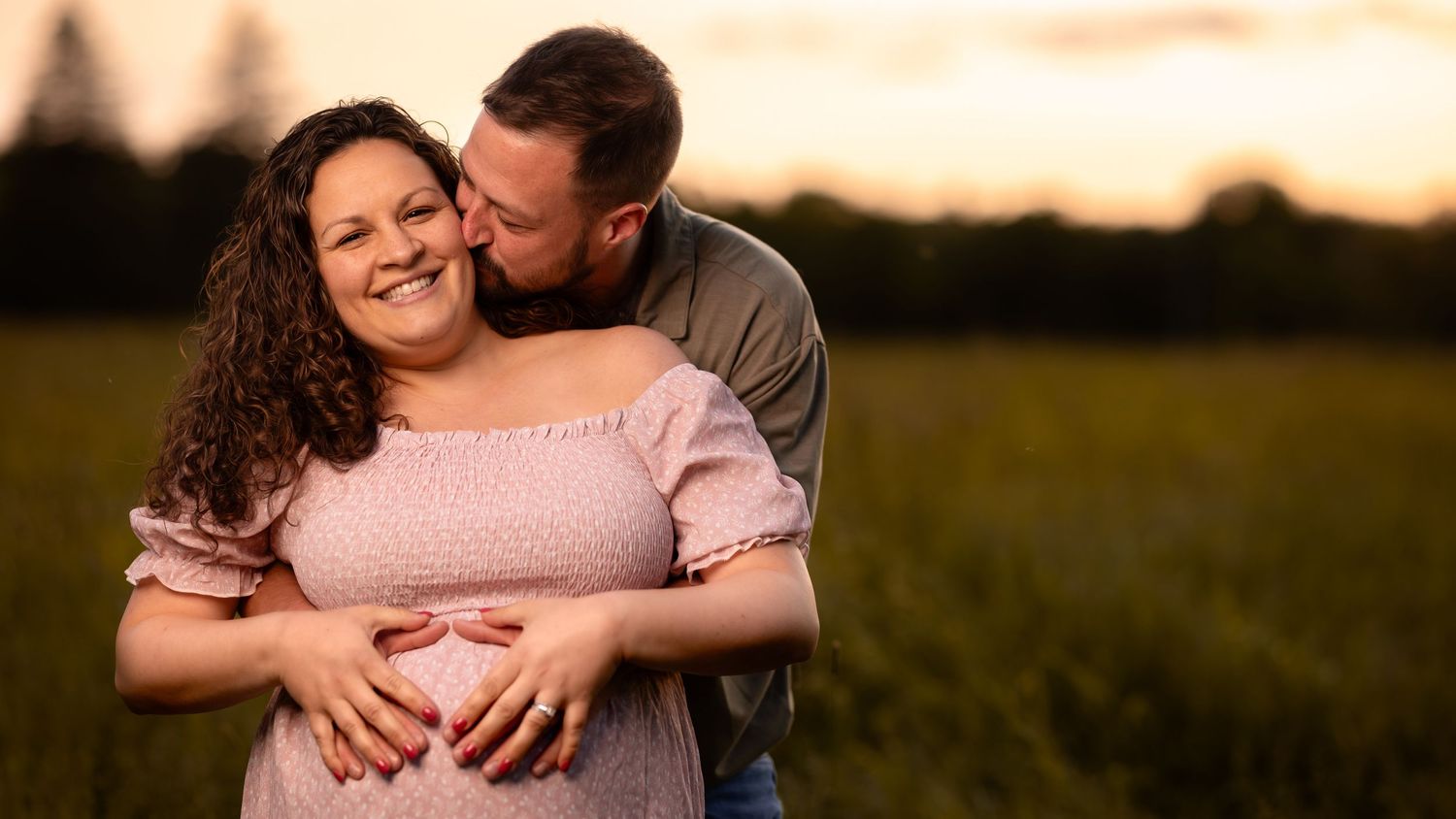 A couple embraces in a golden field during sunset creating a romantic silhouette against the warm sky.