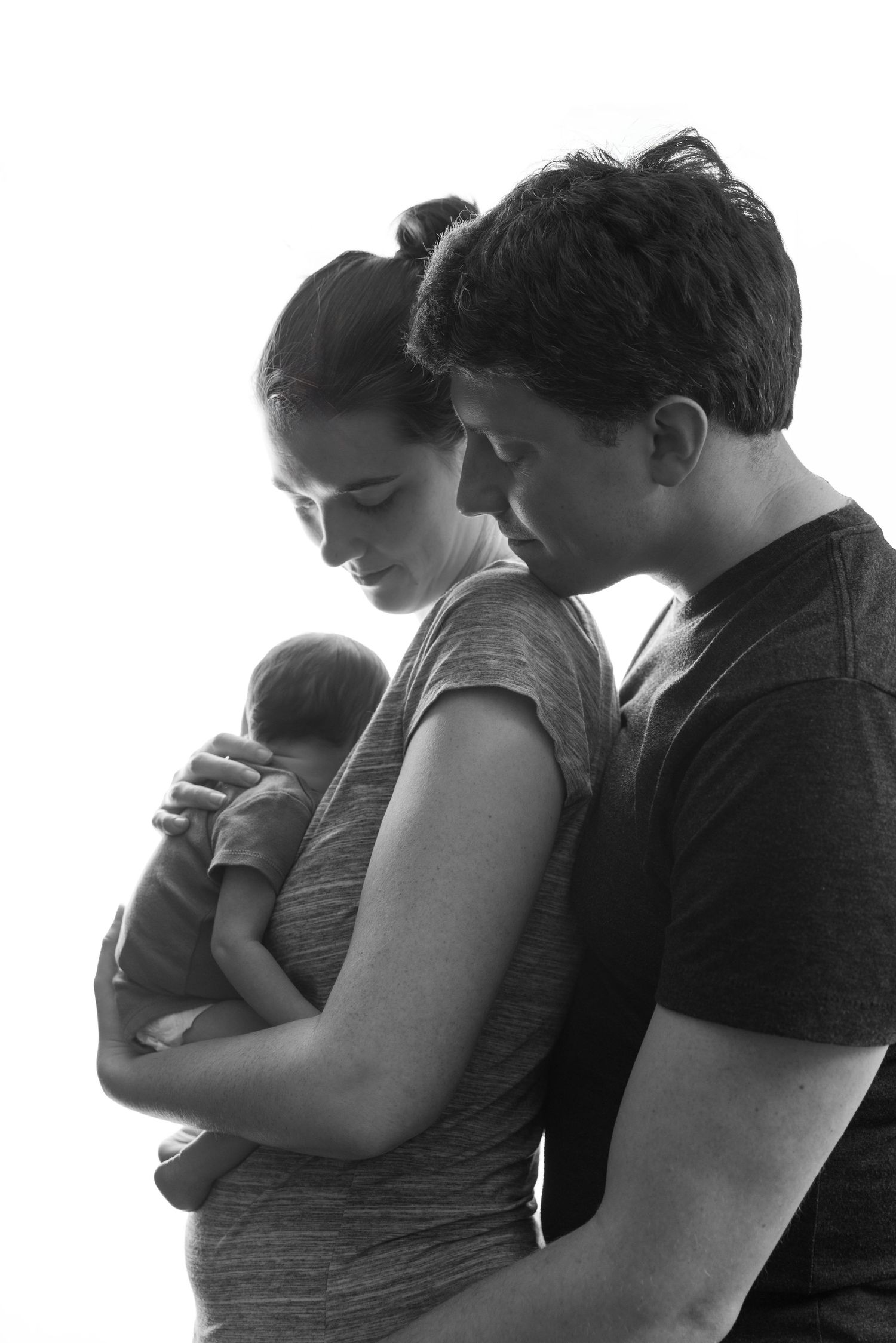 Silhouetted couple holds baby in tender family moment shown in four progressive frames.