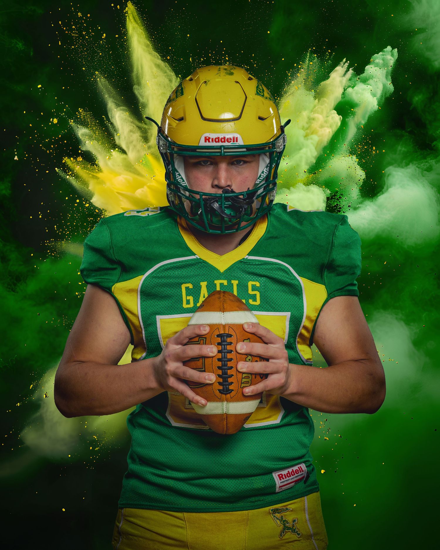 Football player in green and yellow Eagles uniform holds ball against dramatic green and yellow powder explosion background.