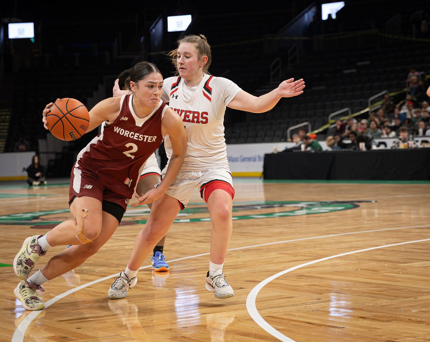 Basketball players dive and reach for a loose ball on the hardwood court during an intense game.