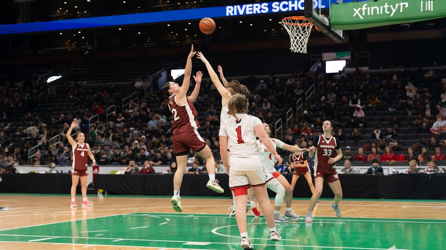 Basketball players compete on the court during a professional game with arena signage visible in the background.