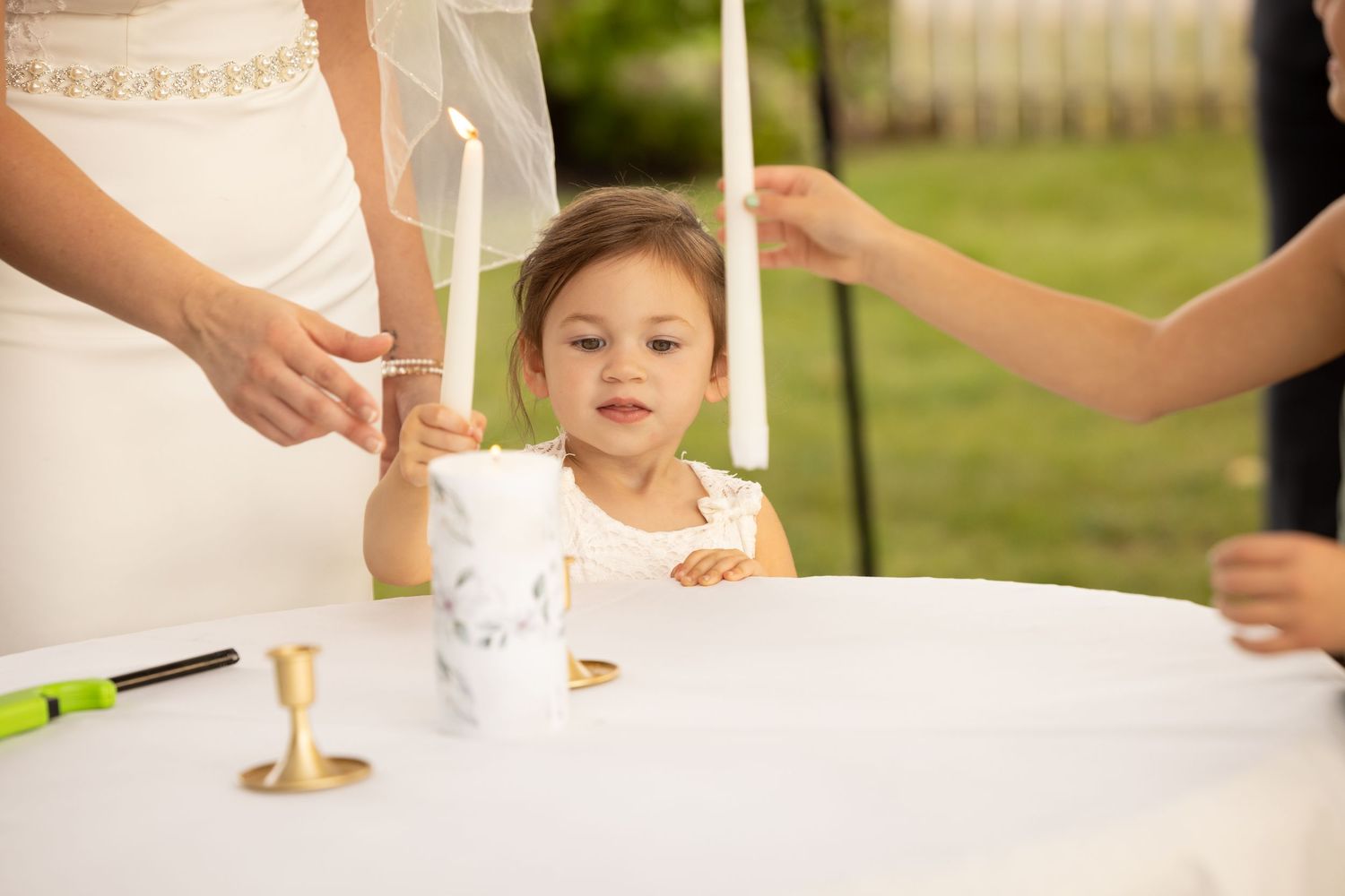 Hands of people playing a cup and ball game with white plastic cups on a wooden surface outdoors.