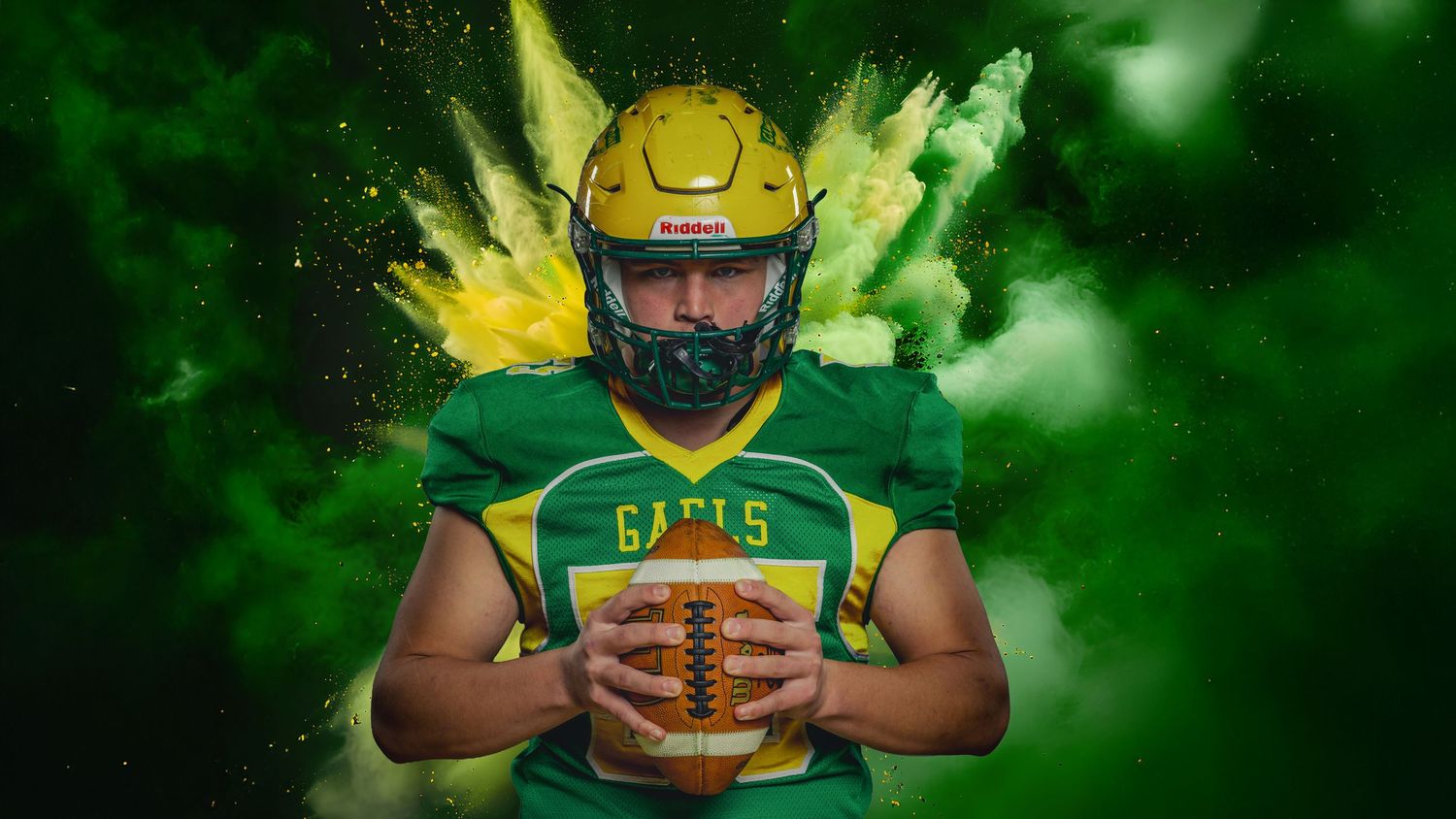 Football player in green and yellow uniform holds ball while posing against dramatic green smoke background.