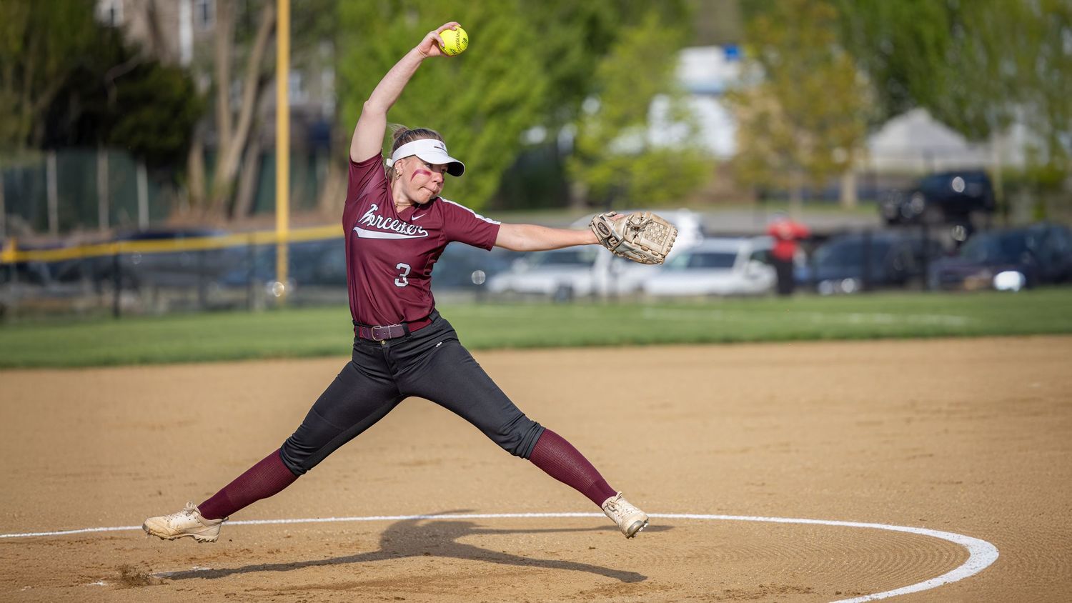 A series of softball players in action poses showing pitching, batting, and fielding on a sunny field during a game.