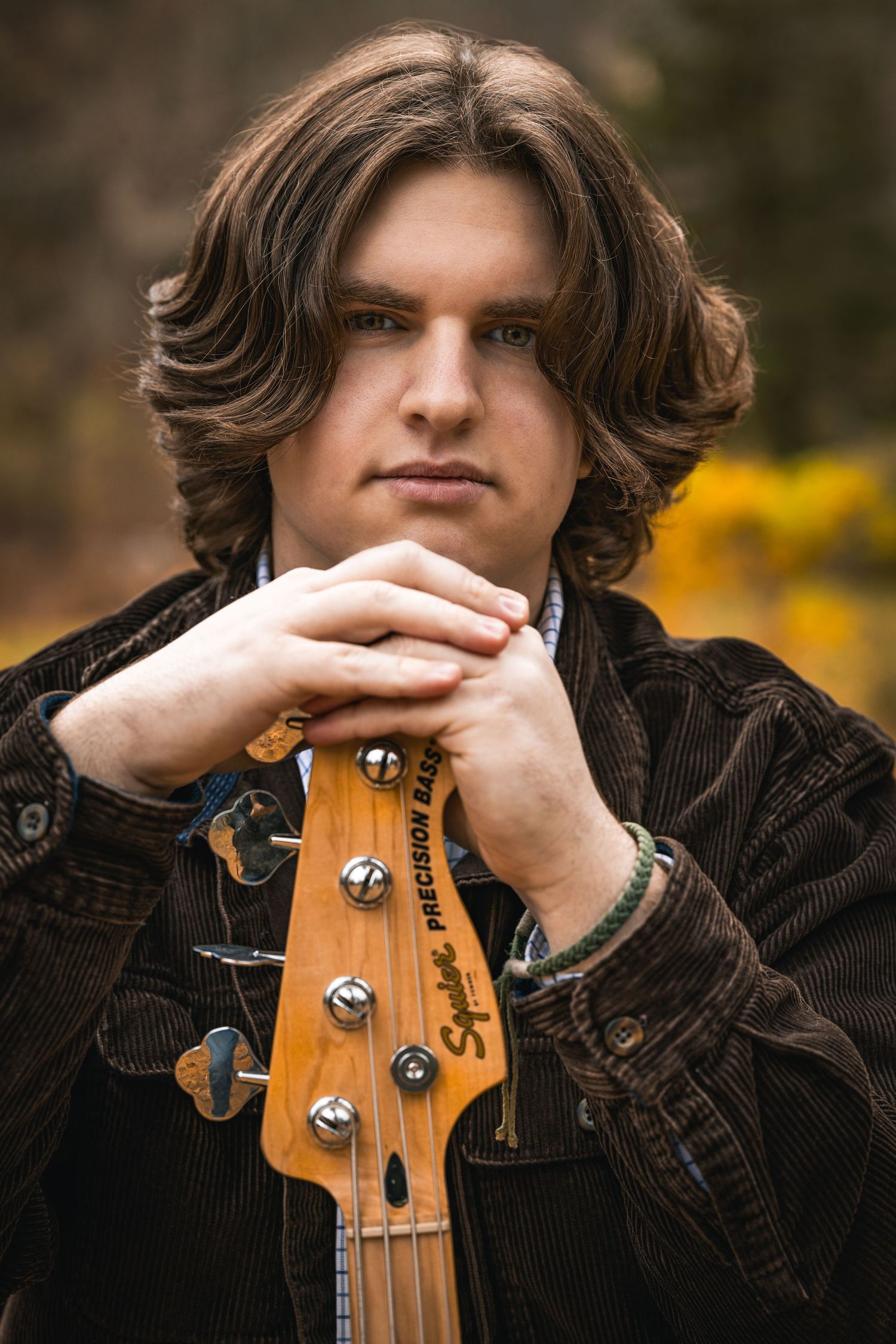 Close-up sequence of a musician with a wooden bass guitar headstock wearing a dark jacket against a blurred background.