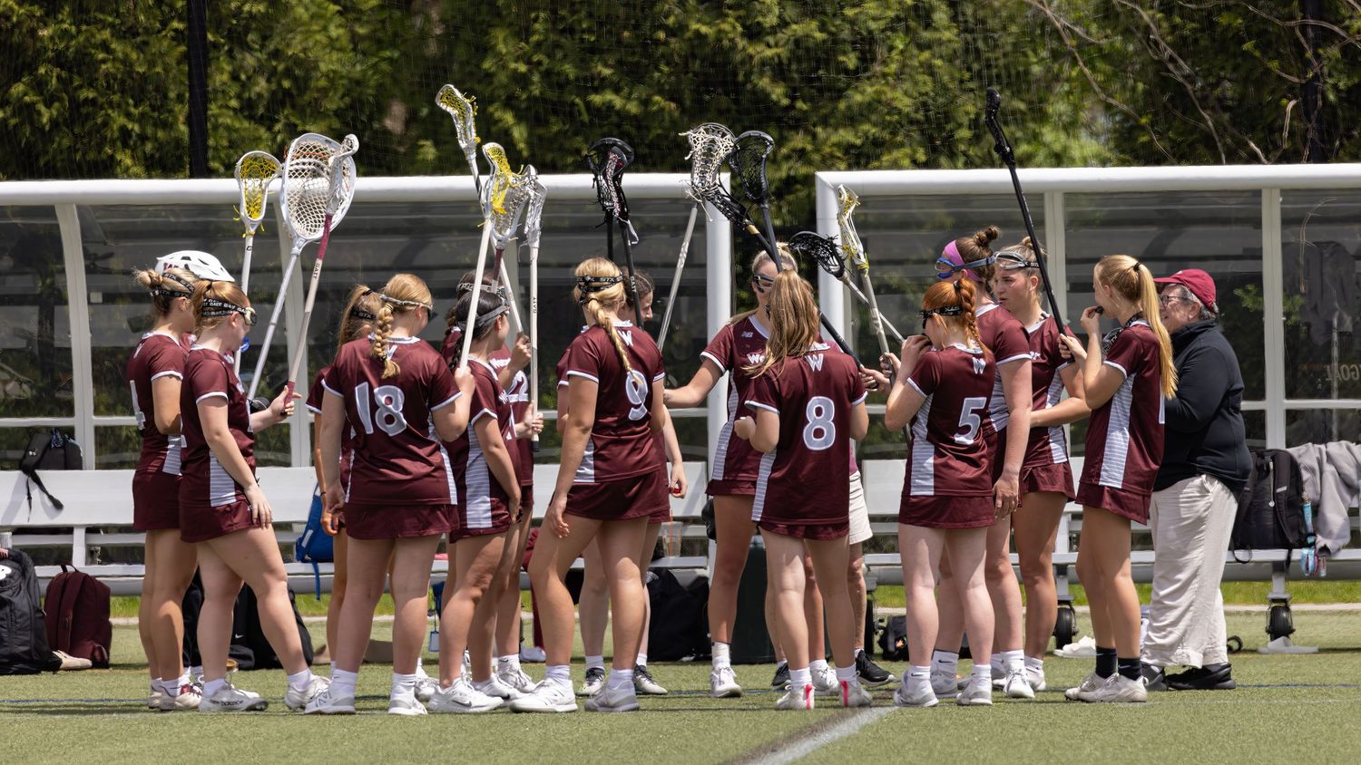 Cheerleaders perform synchronized routine on outdoor field during sunny day with school building in background.