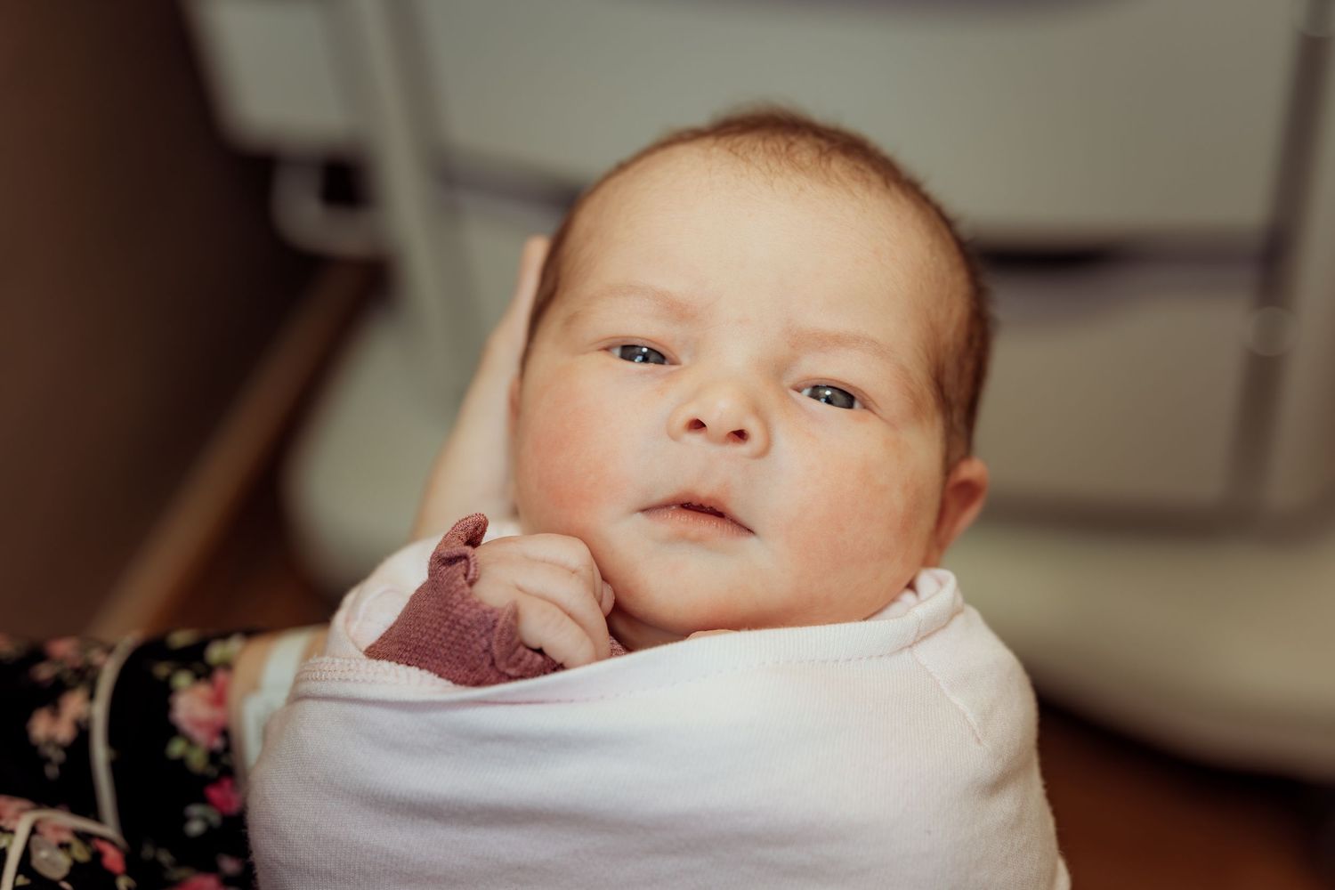 A collage of four images showing a newborn baby swaddled in white blankets in different poses.